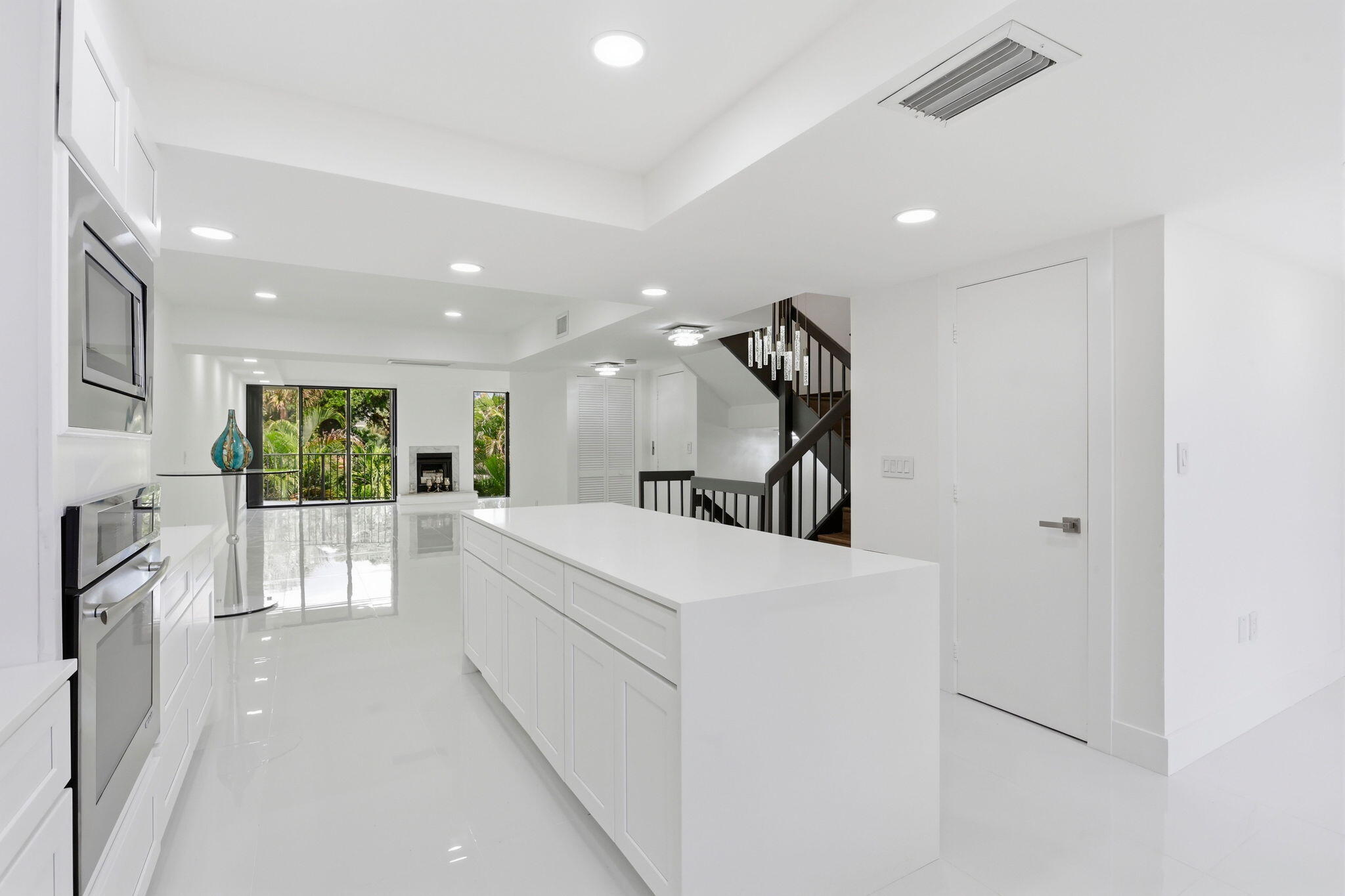 Open-concept kitchen with a large island, integrated stainless steel appliances, recessed ceiling lighting, and hard-surface flooring