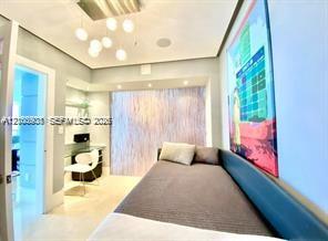 Recessed ceiling lighting, multi-globe pendant light fixture, built-in glass shelving, light-toned stone-finish flooring, and integrated wall paneling