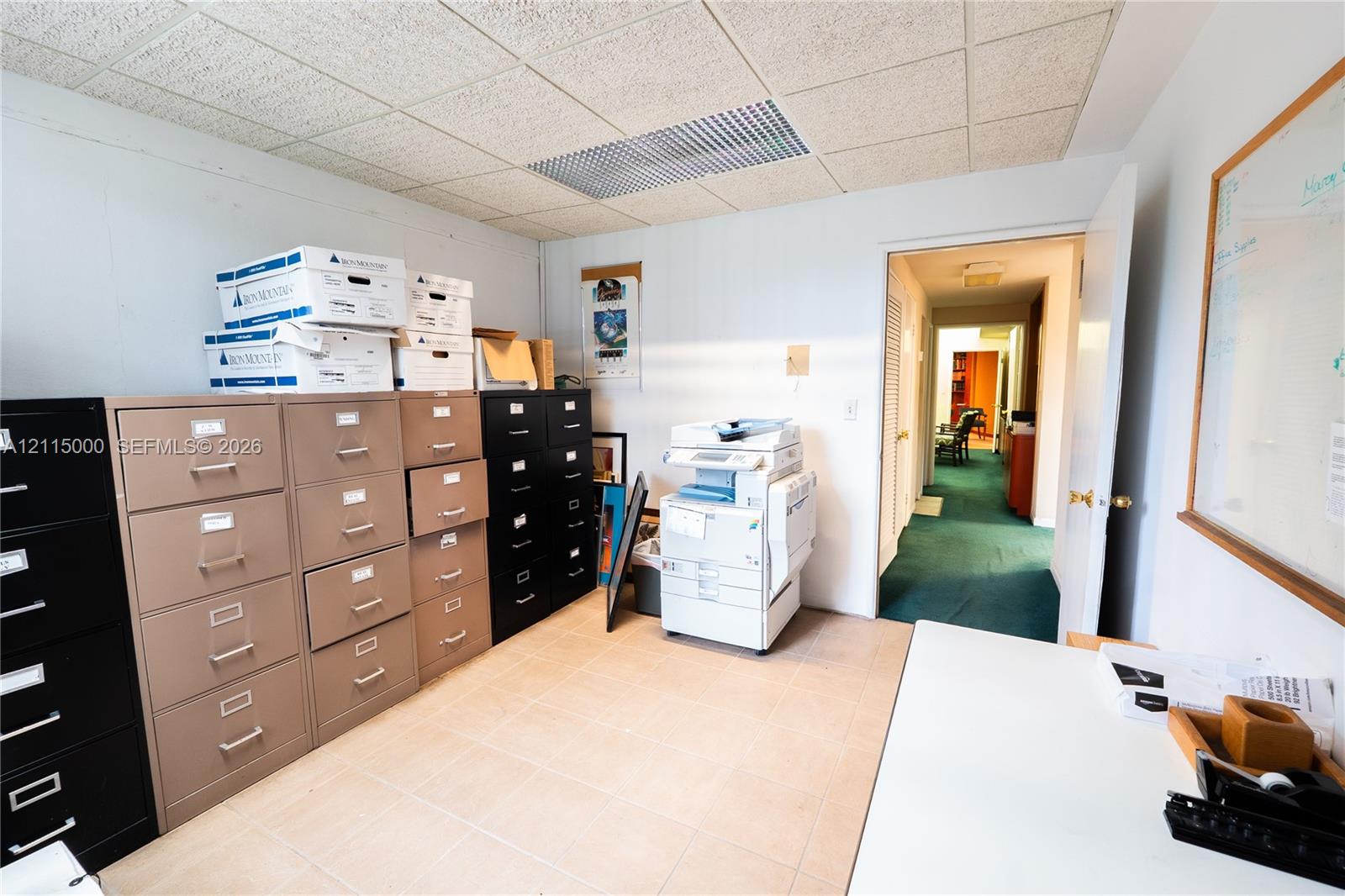 Interior space featuring neutral tile flooring, drop ceiling with integrated lighting panels, and a single-pane window