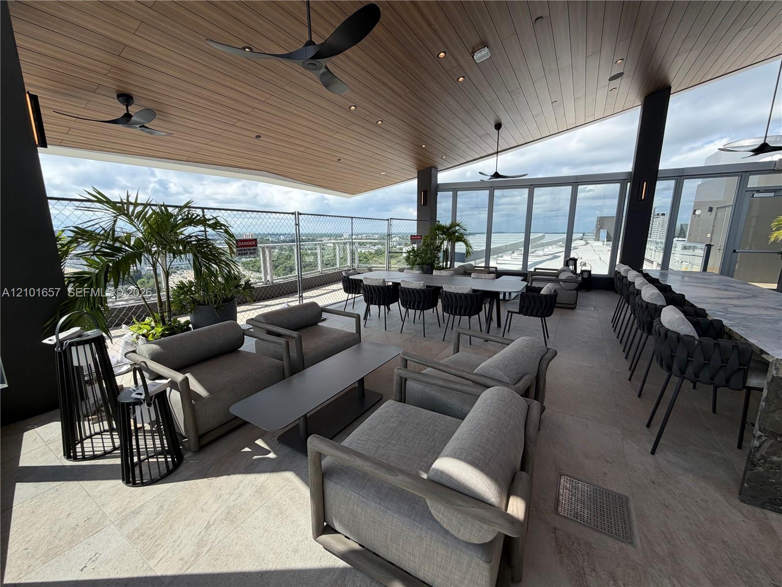 Covered rooftop terrace featuring natural wood-finish plank ceilings, recessed lighting, ceiling fans, stone flooring, and metal railings