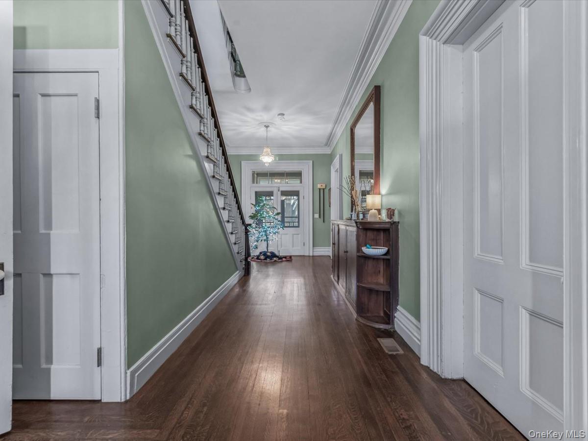 Entrance foyer with 13 ft. ceilings,  plaster crown molding, stairs, and dark wood-style flooring