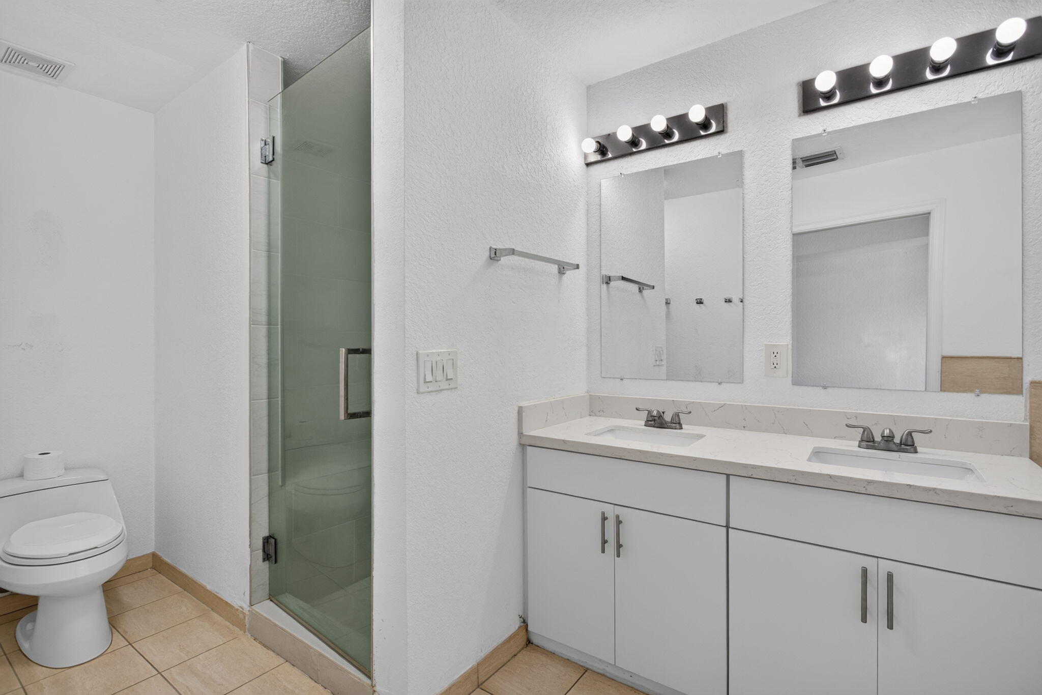 Dual vanity with rectangular undermount sinks, stone countertops, and overhead light fixtures