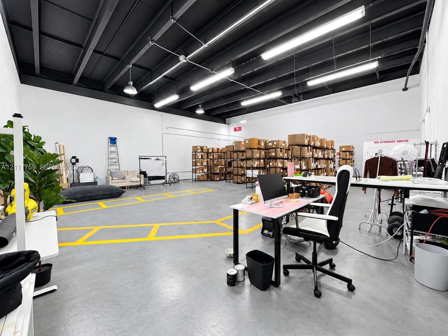 Open-concept industrial space featuring exposed beam ceilings, finished concrete flooring, painted masonry walls, and linear fluorescent lighting
