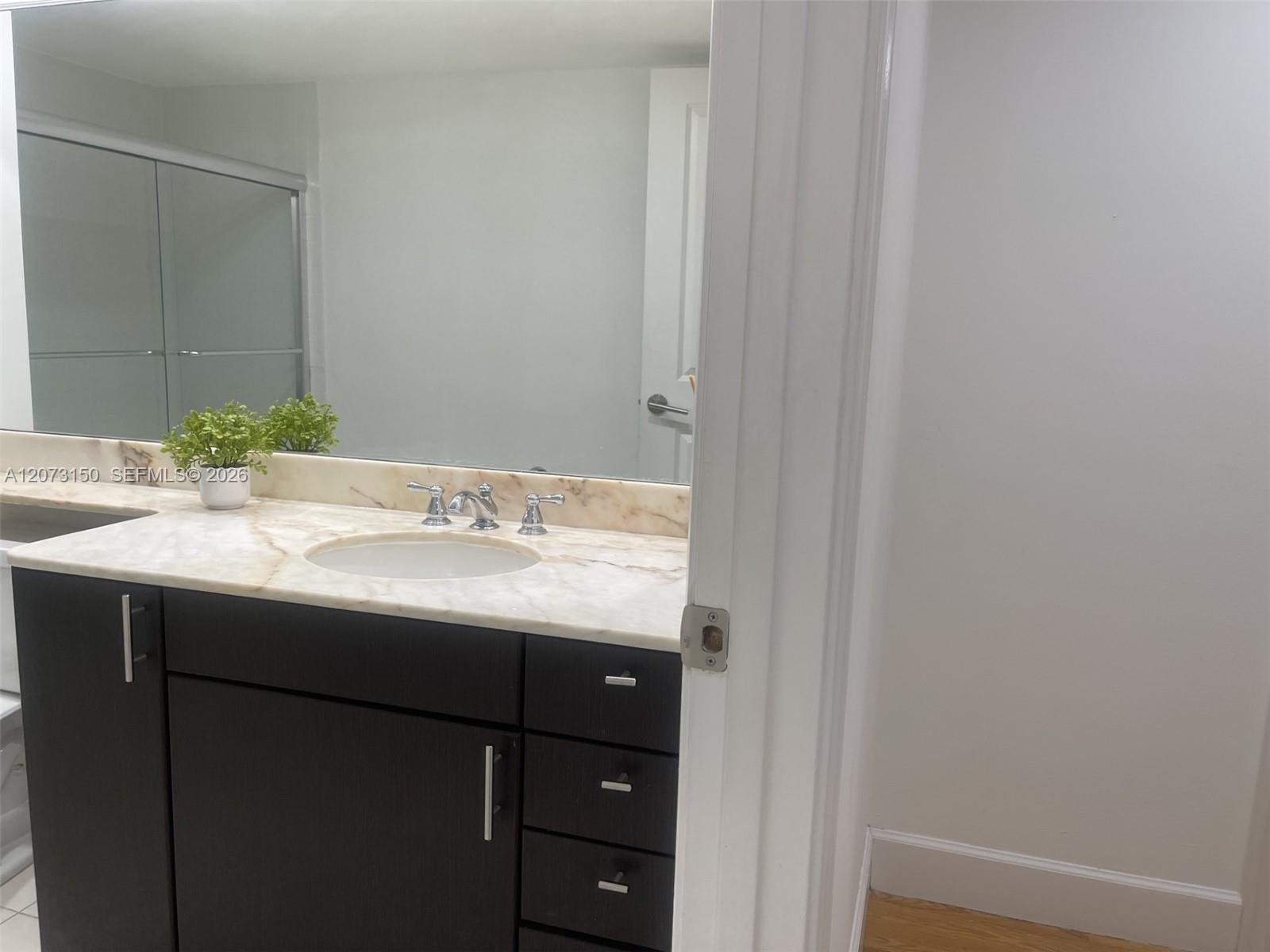 Vanity featuring a dark wood-finish cabinet, stone countertop with a matching backsplash, integrated oval sink, chrome widespread faucet, and full-wid
