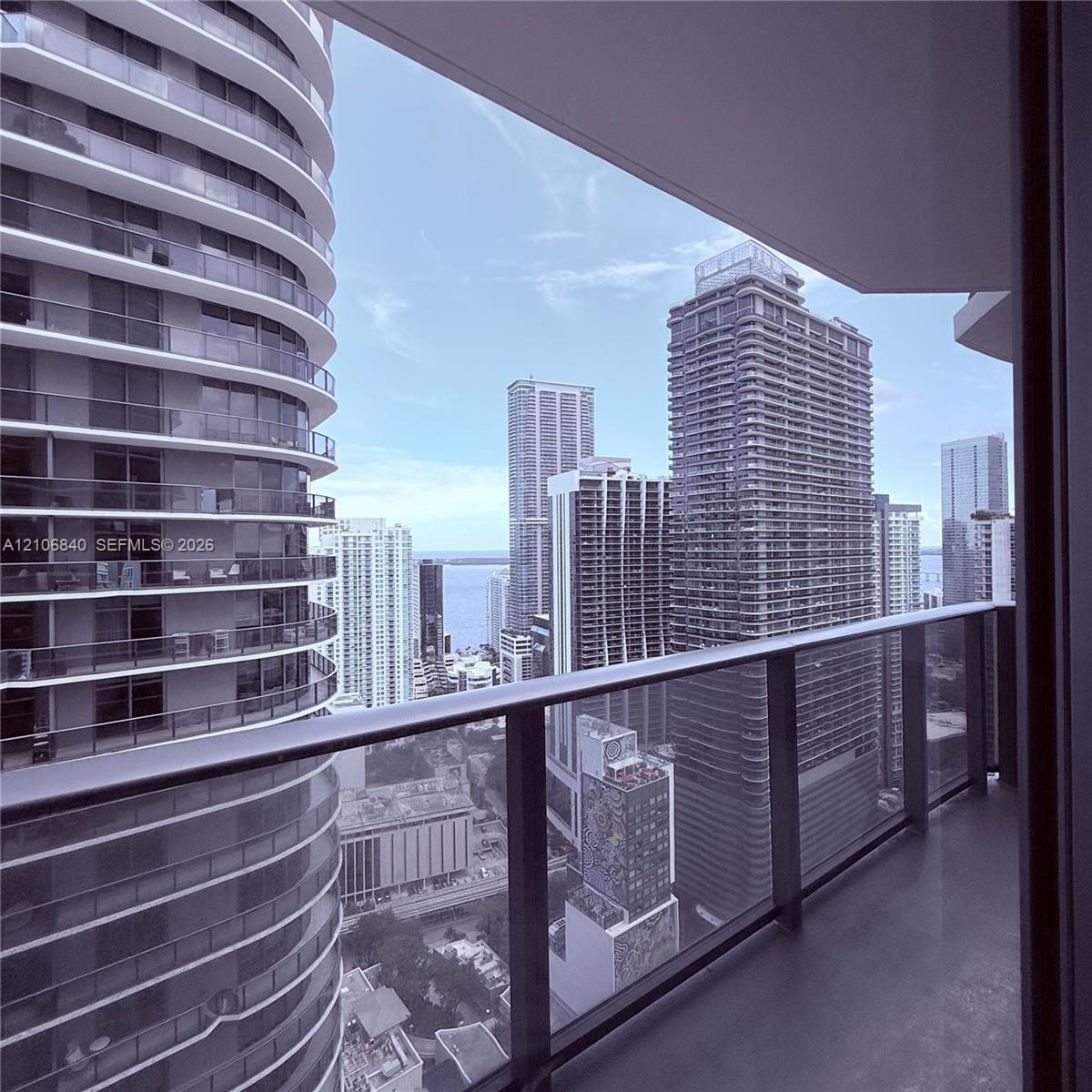 Private balcony featuring glass panel railing and urban skyscraper surroundings