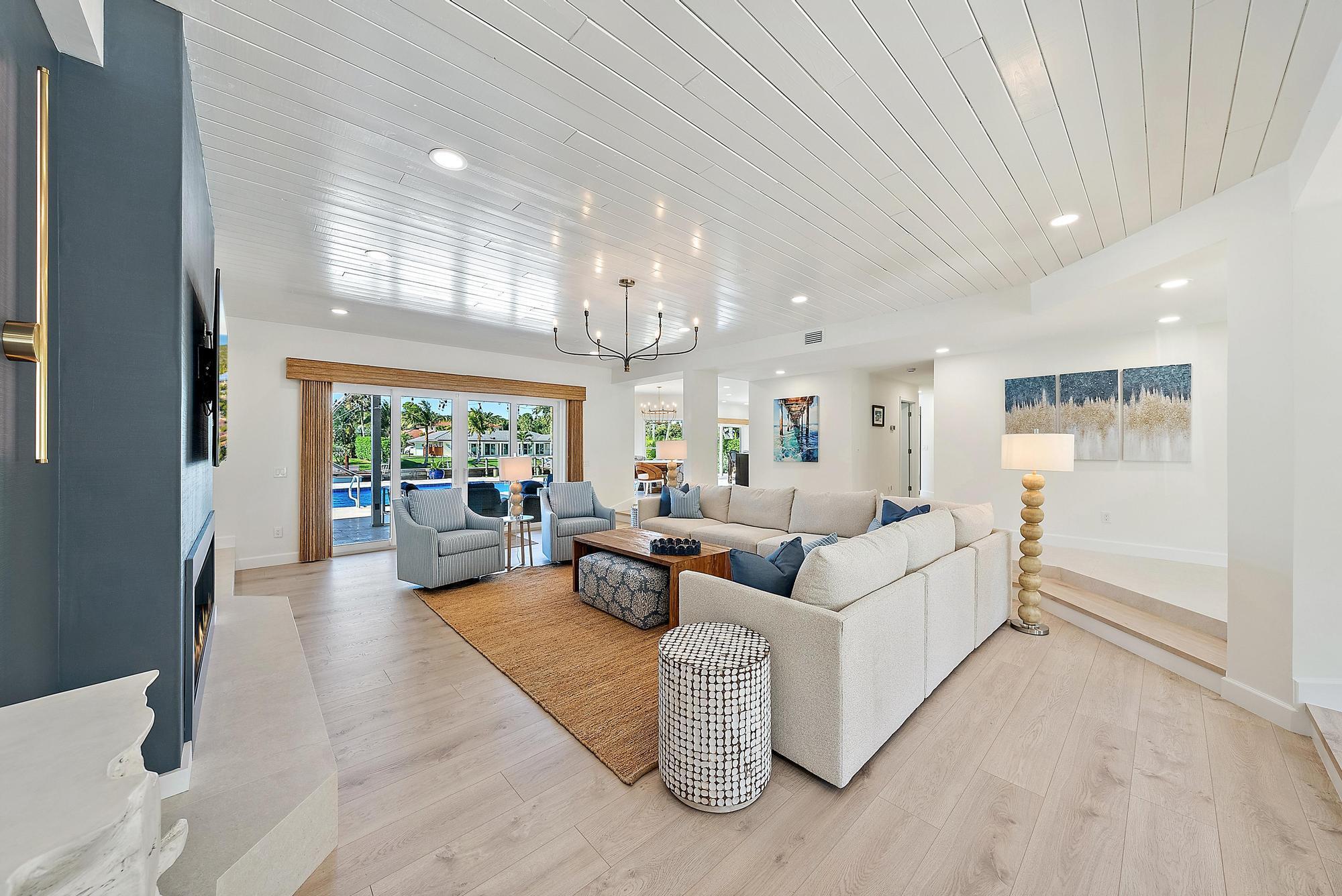 Living area featuring tongue-and-groove vaulted ceilings, wood-finish flooring, a linear fireplace with a floor-to-ceiling surround, recessed lighting