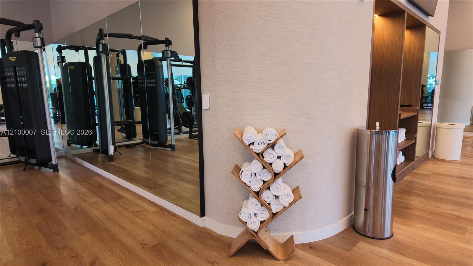 Wood-finish flooring with full-height wall mirrors, built-in shelving, and a beverage dispenser