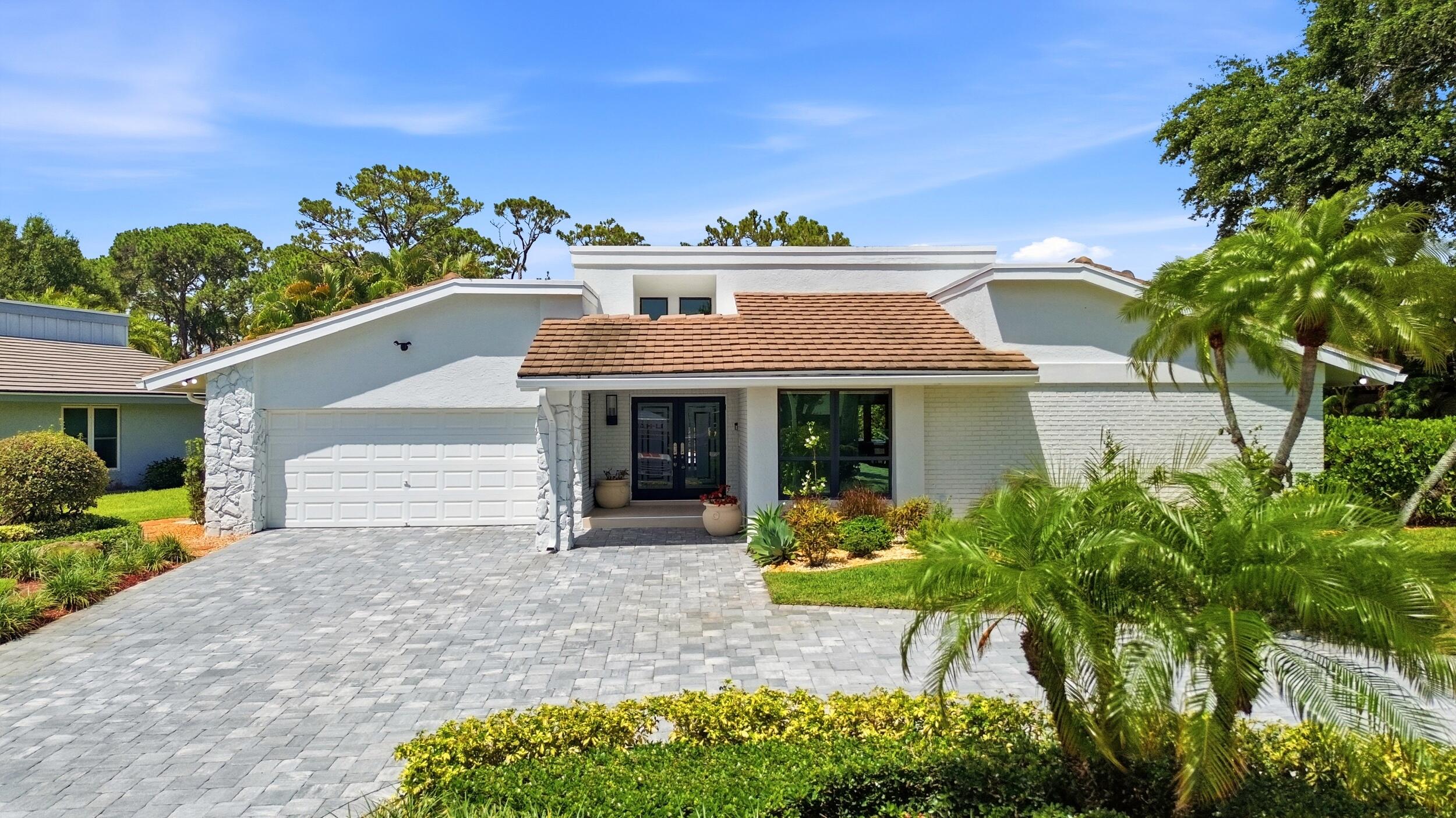 A striking first impression begins with a sweeping paver driveway, lush tropical landscaping, and timeless architectural details that set this home ap