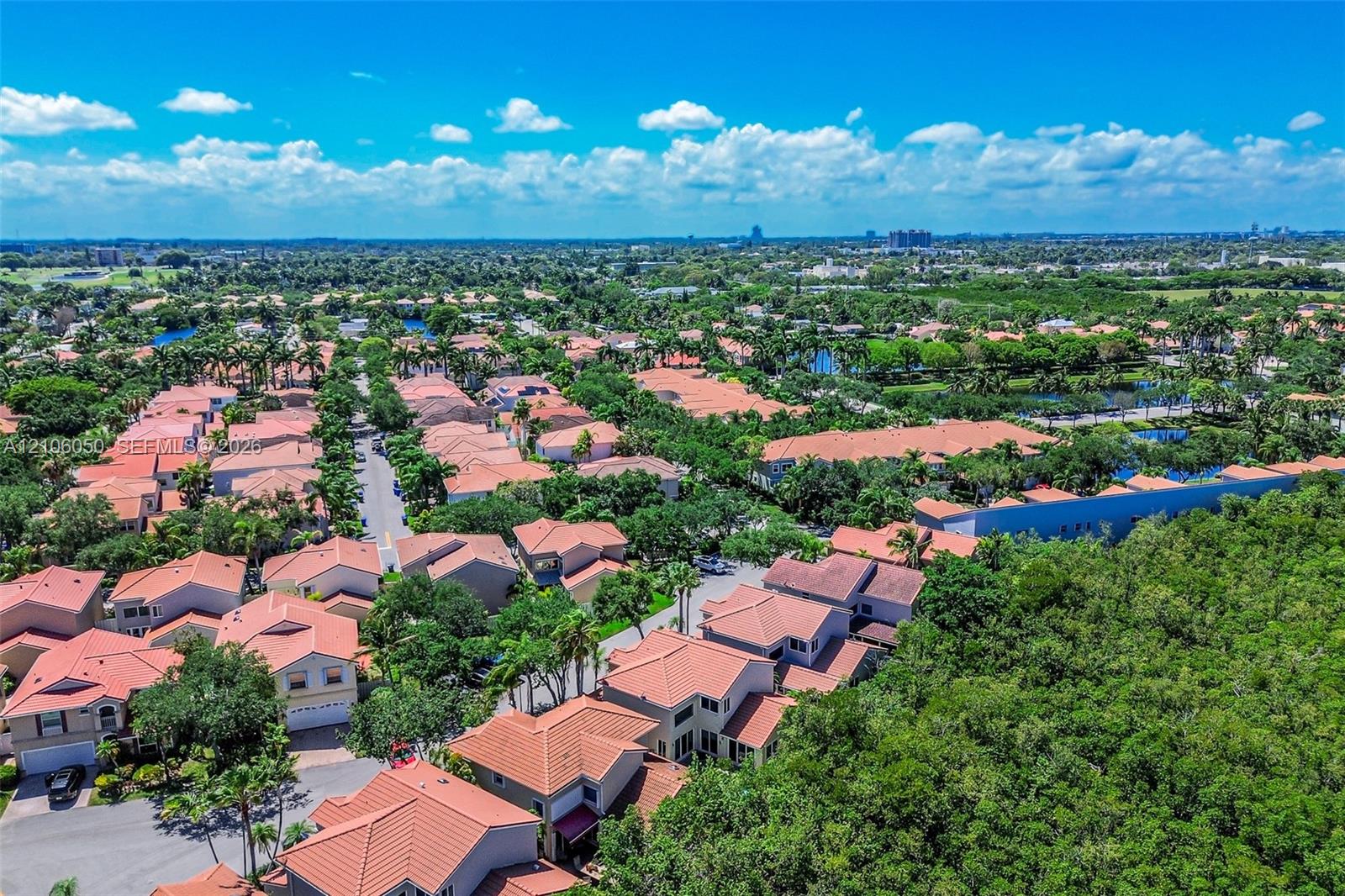 Aerial perspective featuring residential tile roofing, mature canopy trees, and established landscaped grounds