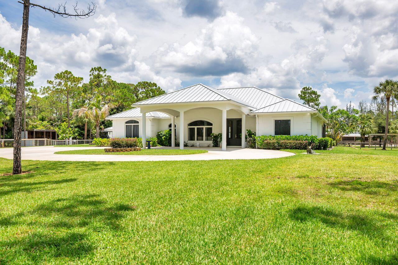 White stucco exterior with a metal roof and an arched portico entry