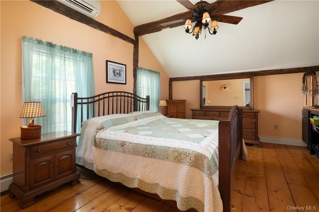 Bedroom with vaulted ceilings and beams, ceiling fan, lofted ceiling, light hardwood , and a wall mounted AC
