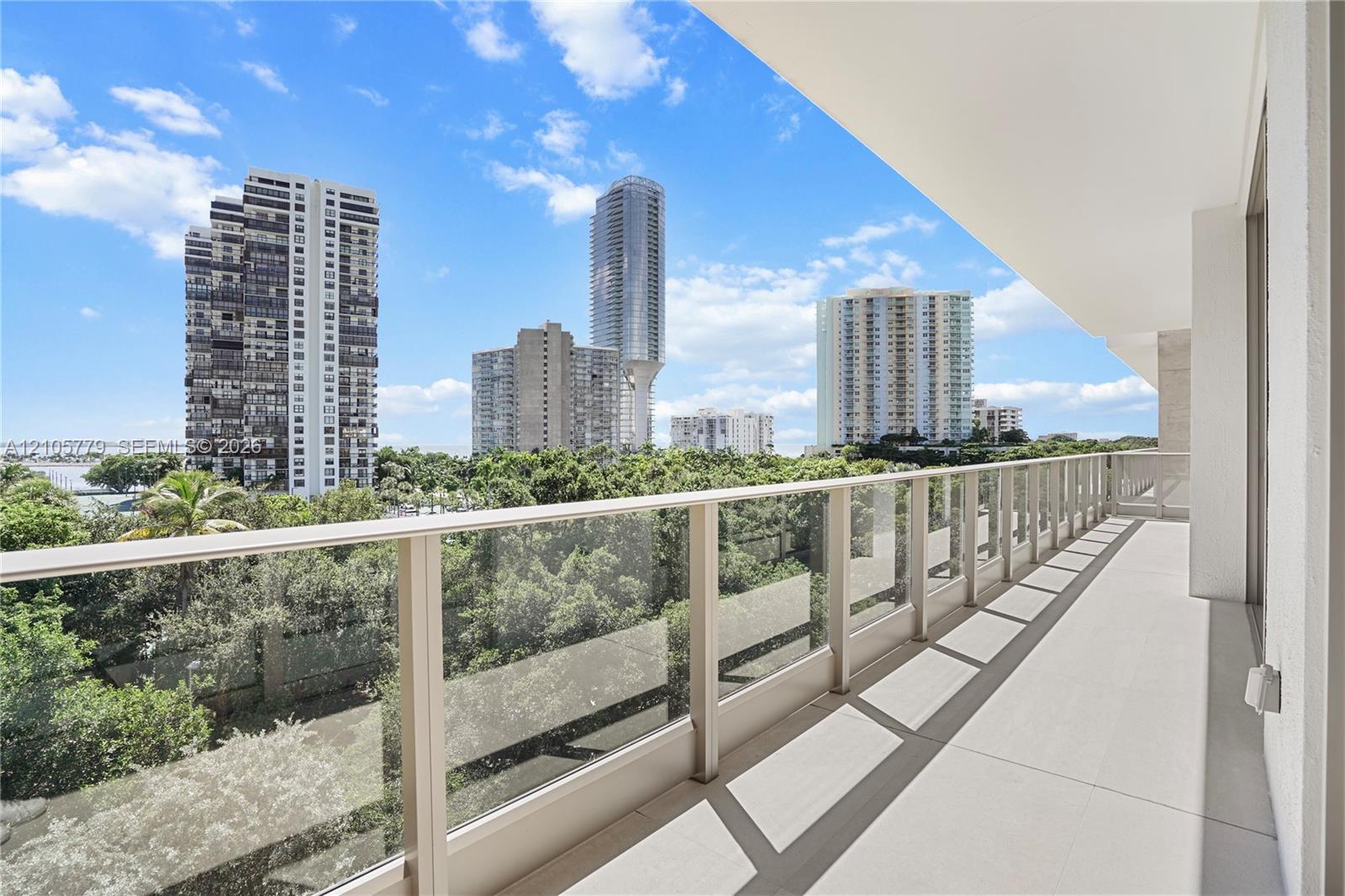 Spacious balcony featuring light-toned tile flooring and a glass-paneled railing