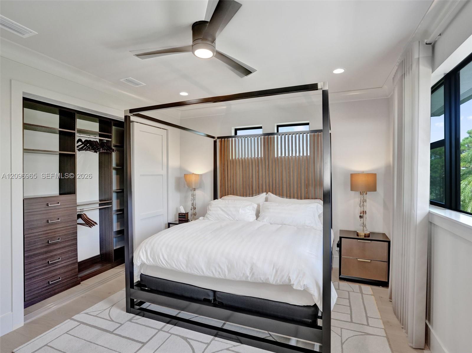 Custom built-in closet with integrated drawer storage and shelving, ceiling fan with light kit, crown molding, and clerestory windows