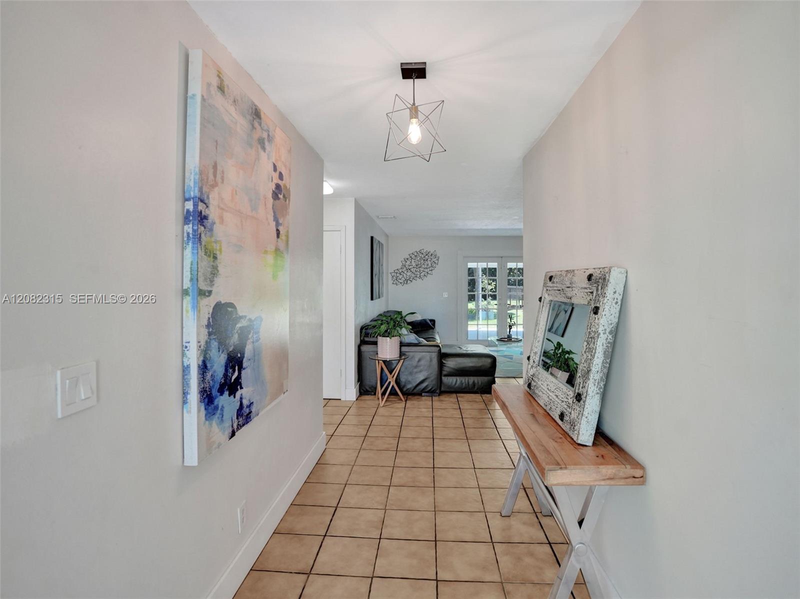 Entryway featuring ceramic tile flooring, neutral wall paint, and a geometric-style metal pendant light fixture