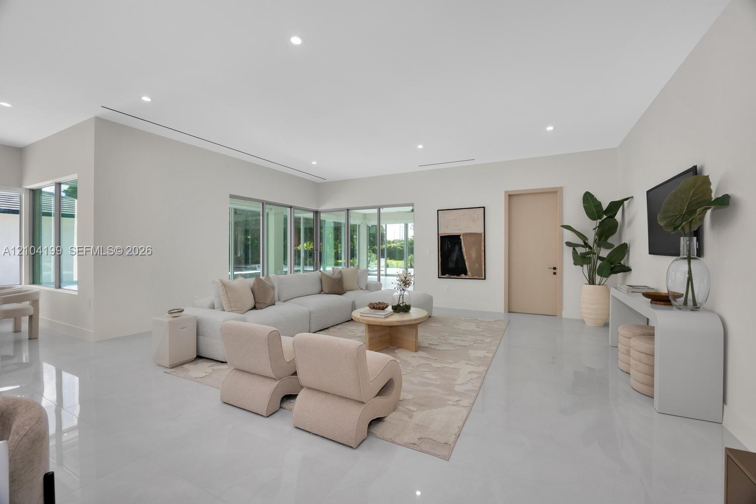 Spacious interior featuring large-format tile flooring, recessed lighting, expansive glass windows, and minimalist trim-less door frames