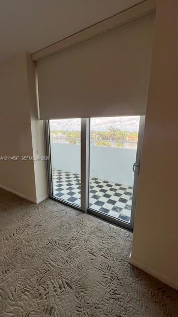 Sliding glass door with integrated roller shade, leading to a private balcony featuring a checkered tile floor and metal railing