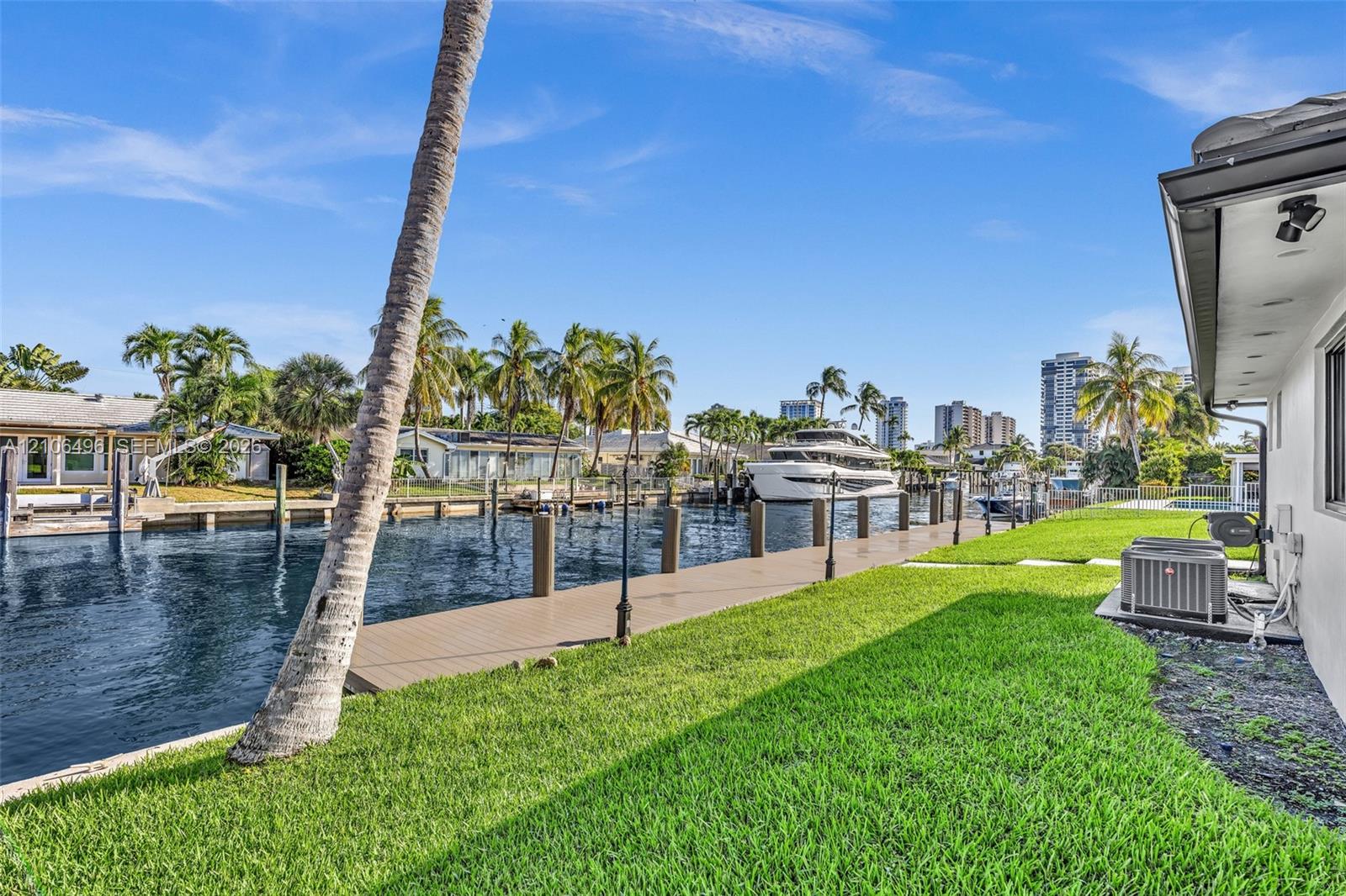 Waterfront property featuring a private dock, bulkhead, and manicured lawn