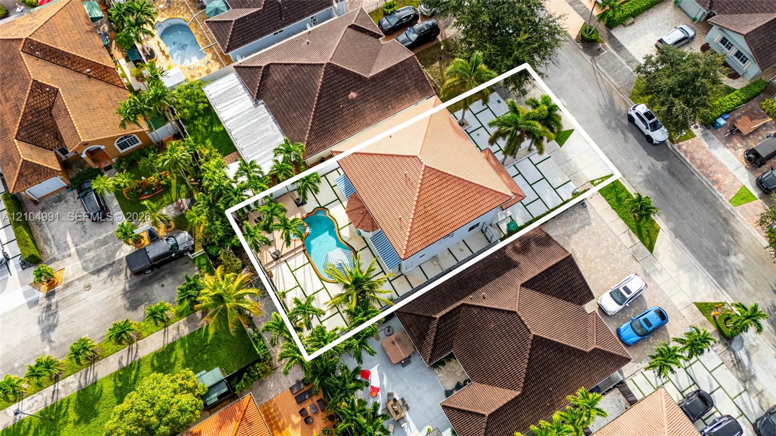 Aerial perspective featuring a tile roof, an in-ground swimming pool, and geometric paver hardscaping