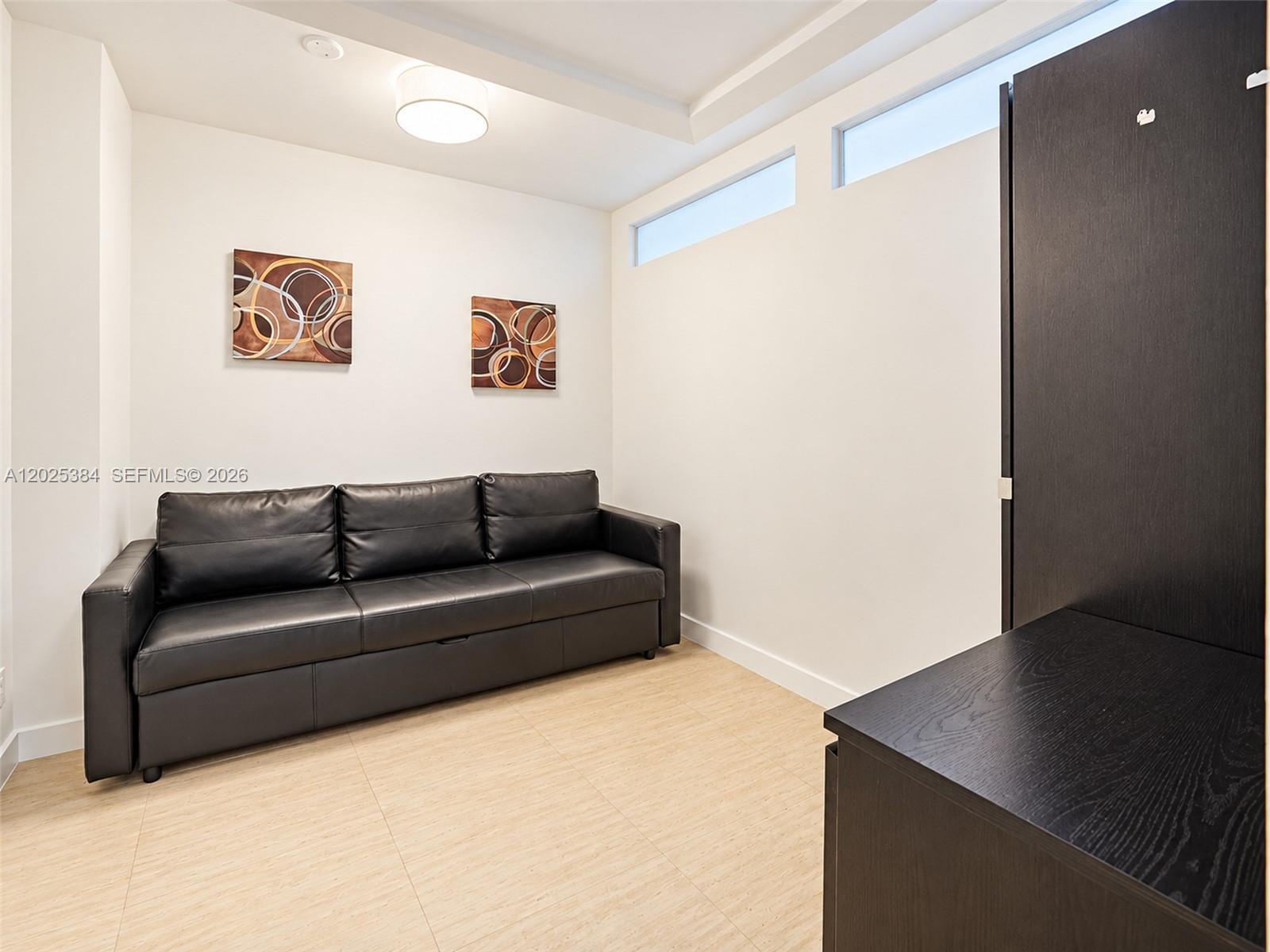 Wood-finish flooring, high-level transom windows, flush-mount ceiling lighting, and built-in dark cabinetry