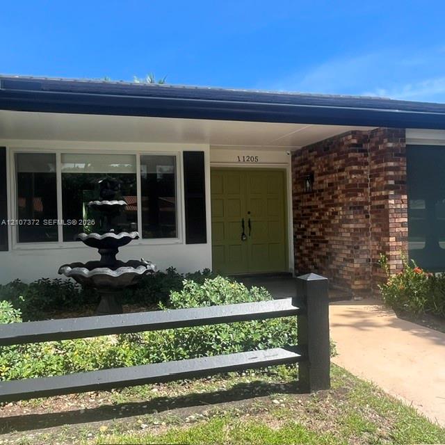 Exterior entry featuring double front doors, multi-tier decorative fountain, brick facade, and black post-and-rail fencing