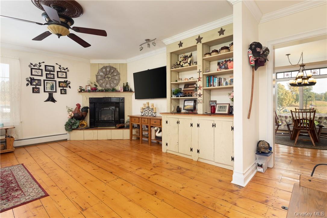 Living room with light hardwood, built ins, ornamental molding, and a propane fireplace
