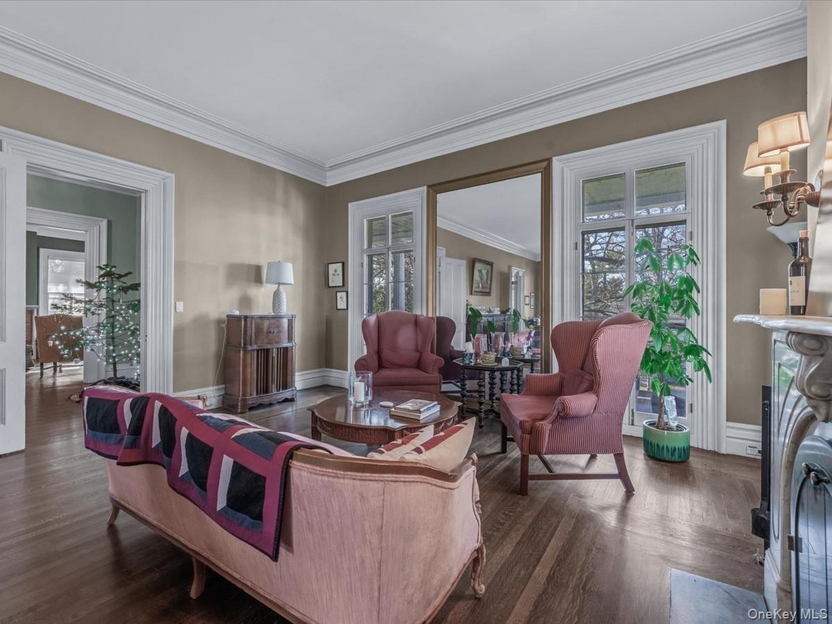 Living room with healthy amount of natural light, dark wood-style floors, a fireplace, and ornamental molding