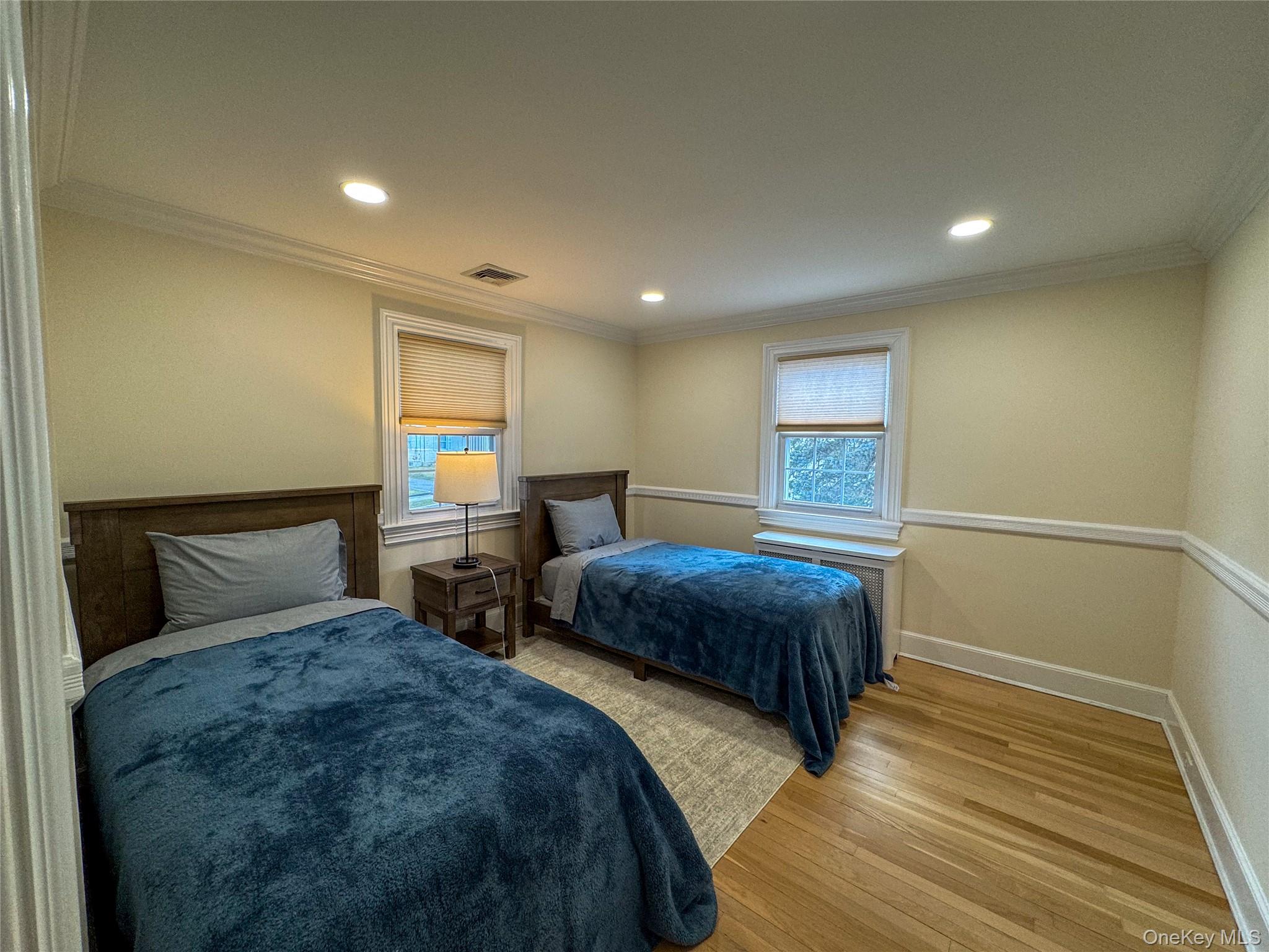 Recessed ceiling lighting, crown molding, wood-finish flooring, two windows with blinds, and wainscoting