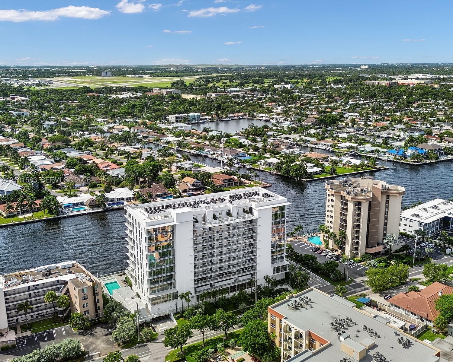 High-rise building featuring extensive glass facade, private balconies, a ground-level swimming pool, and direct waterfront positioning