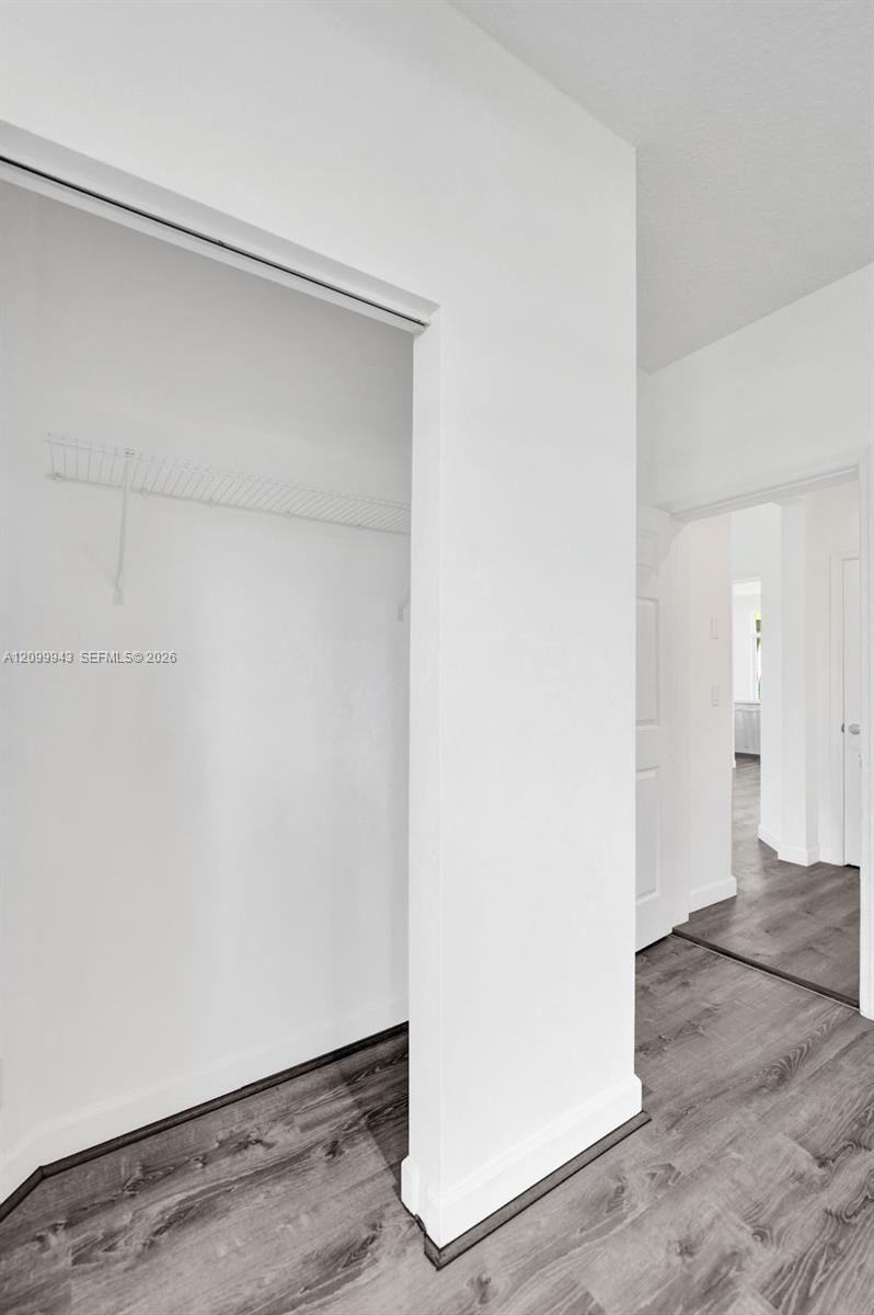 Reach-in closet featuring wire shelving and wood-finish flooring