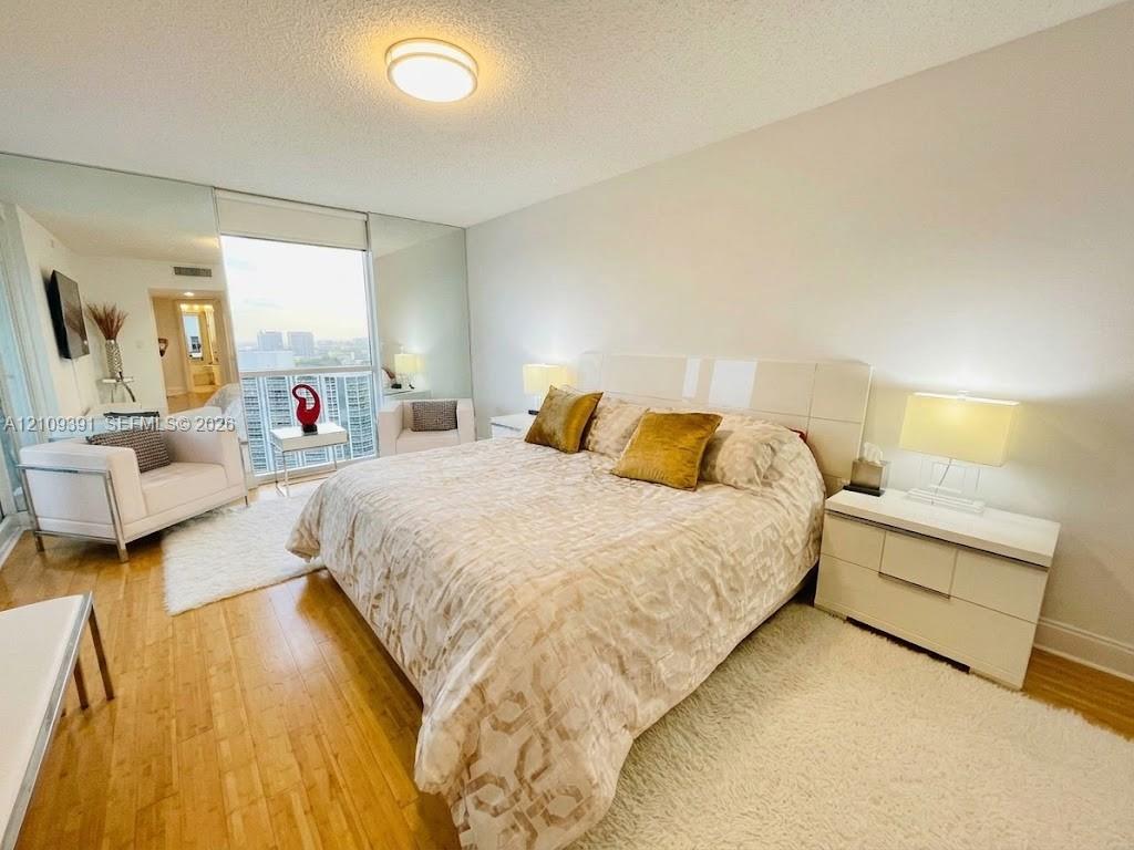 Wood-finish flooring, full-height mirrored wall panels, and floor-to-ceiling glass sliding door with exterior access