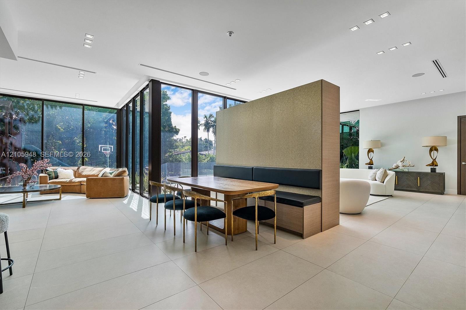 Open-concept interior featuring expansive floor-to-ceiling windows, large-format tile flooring, recessed ceiling lighting, and a custom architectural 