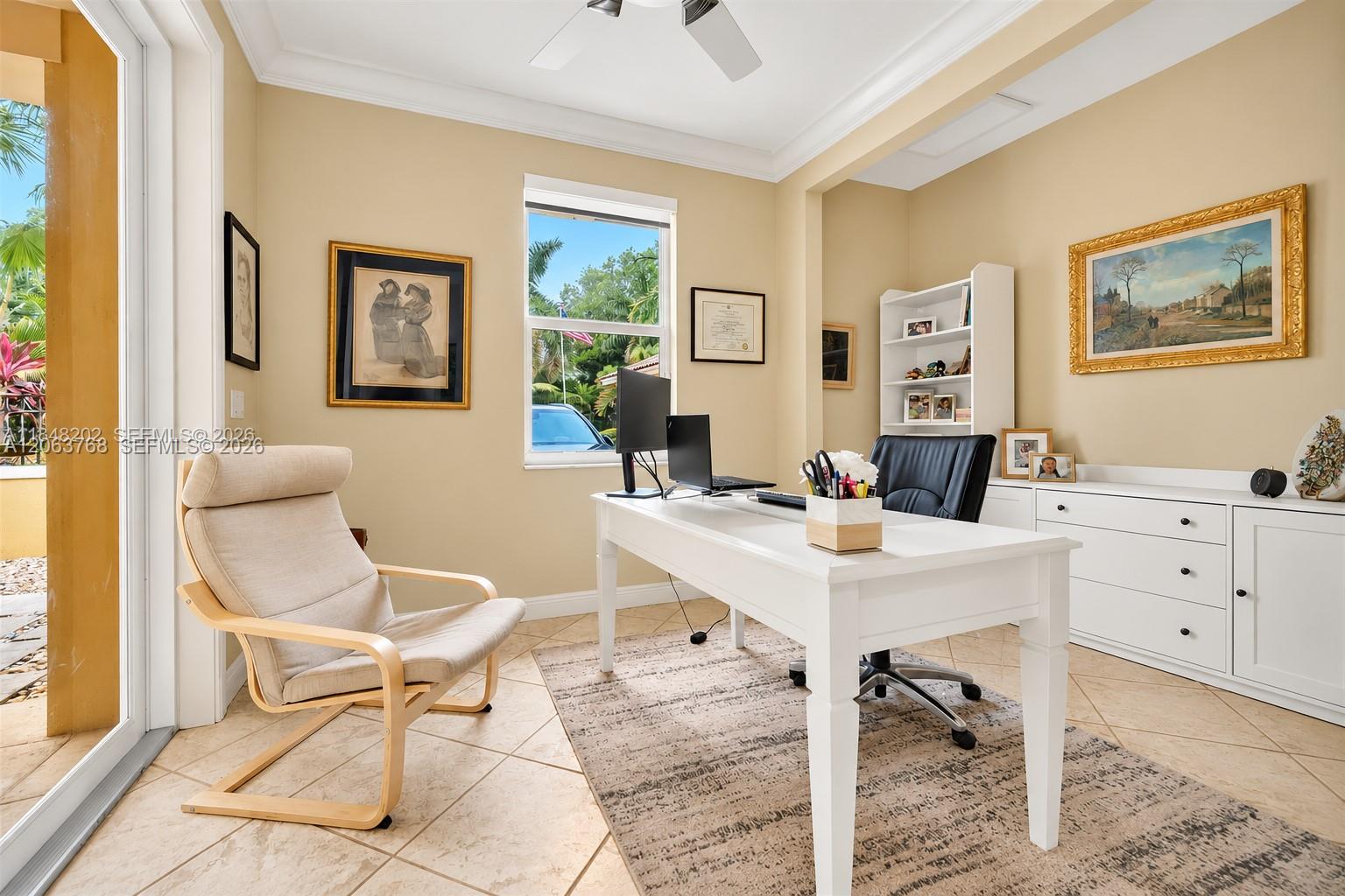 Room featuring tile flooring, crown molding, built-in white cabinetry, a white shelving unit, and a sliding glass door