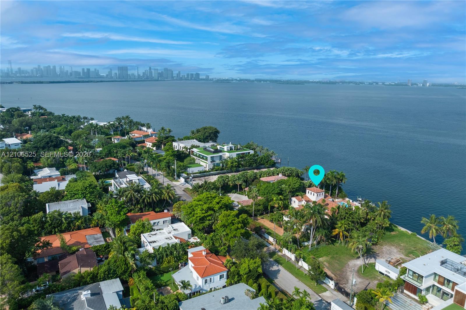 Aerial perspective of a waterfront property featuring direct water frontage, a multi-story residence with a red tile roof, and mature perimeter landsc