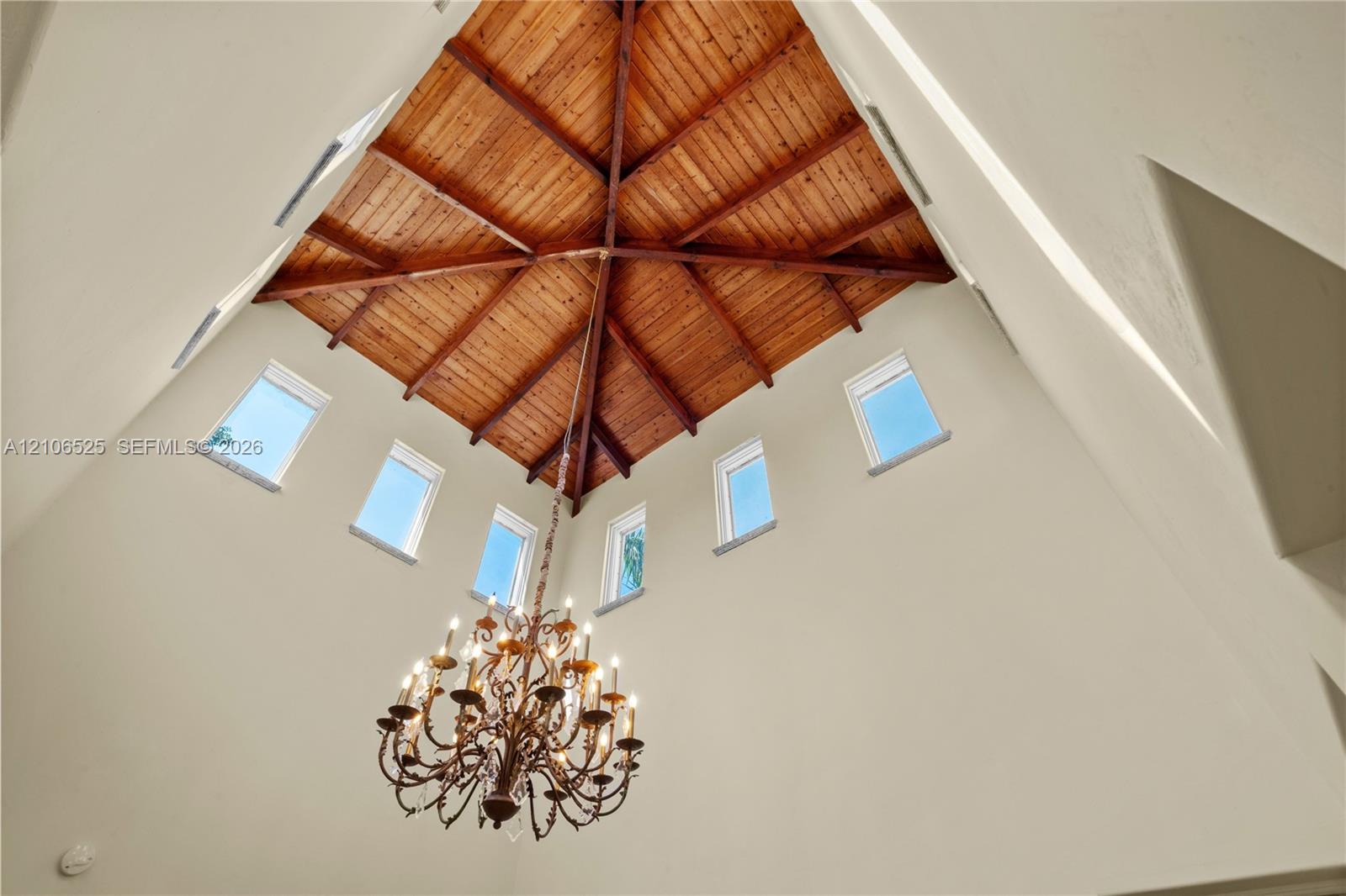 Vaulted ceiling with exposed wood-plank beams, clerestory windows, and a multi-tiered metal chandelier