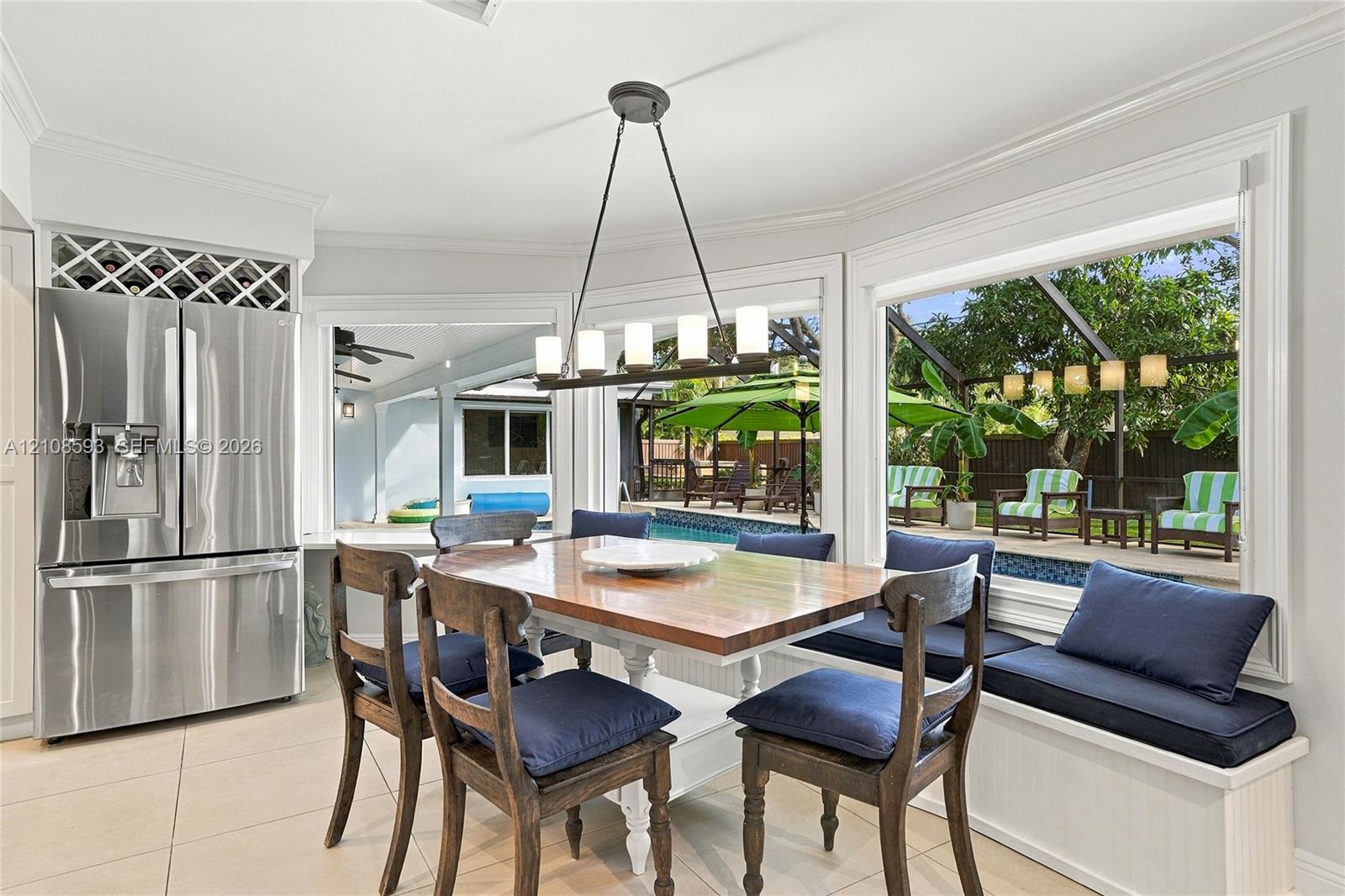 Dining area featuring large-format tile flooring, built-in window seating with integrated storage, stainless steel refrigerator with overhead wine rac
