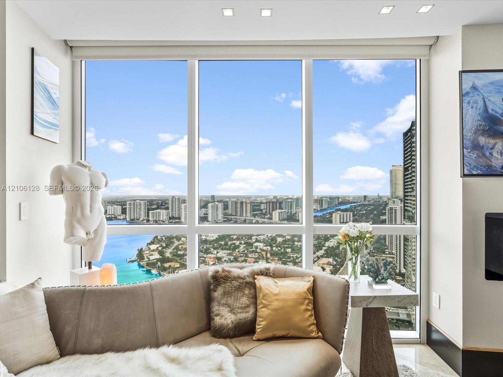 Floor-to-ceiling windows featuring expansive urban and waterway scenery, complemented by recessed ceiling lighting