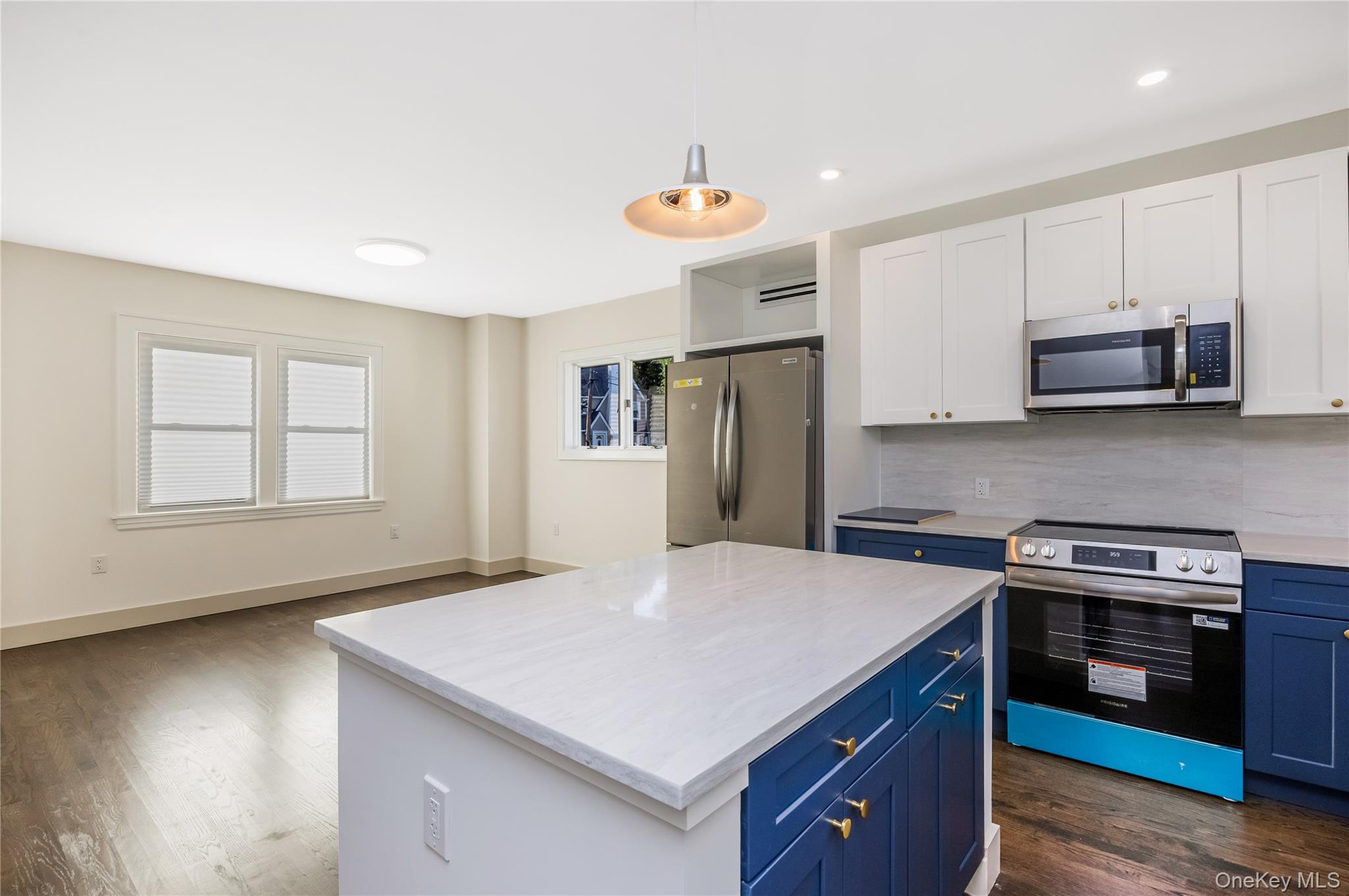 Eat in kitchen leading into the dining room featuring two-tone navy and white shaker cabinetry, quartz countertops, stainless steel appliances, a cent