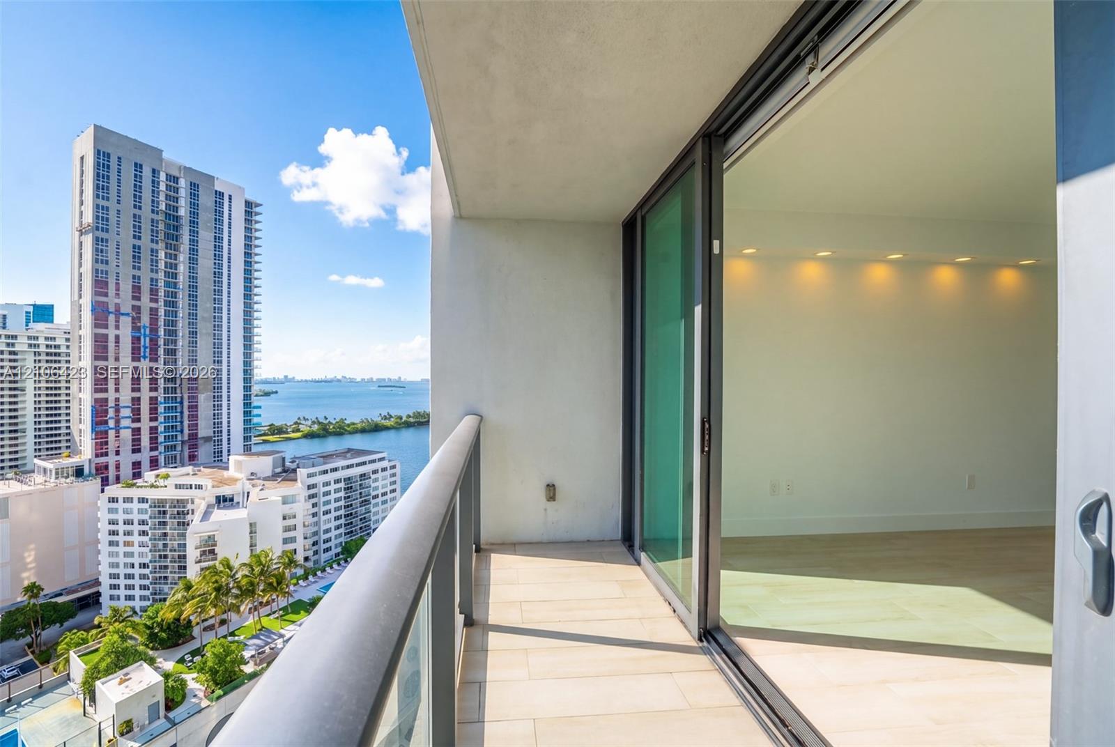 Covered balcony featuring tile flooring, metal railing with glass panels, and sliding glass door entry to interior space with recessed ceiling lightin
