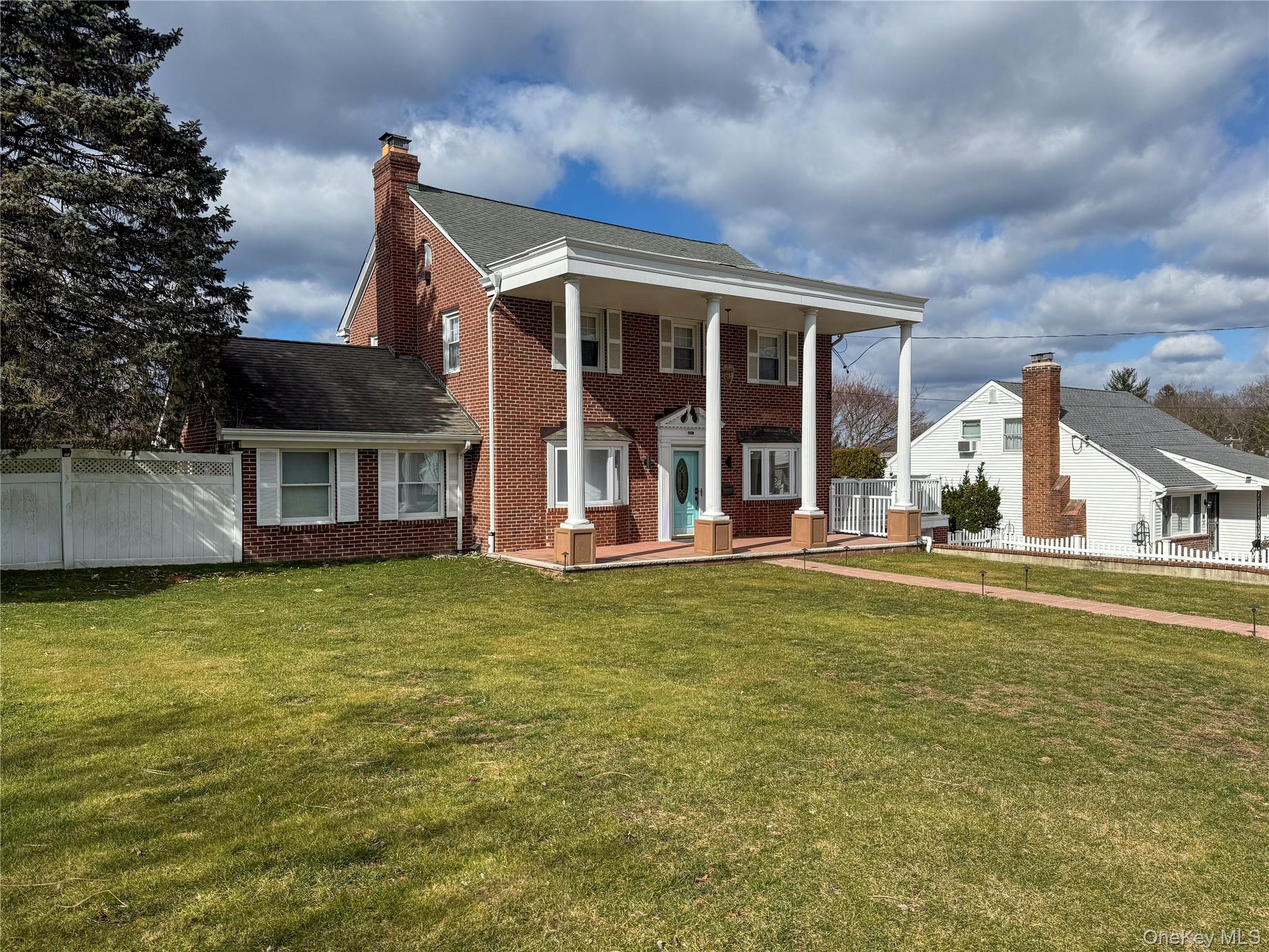 Brick exterior with white columned portico and turquoise entry door