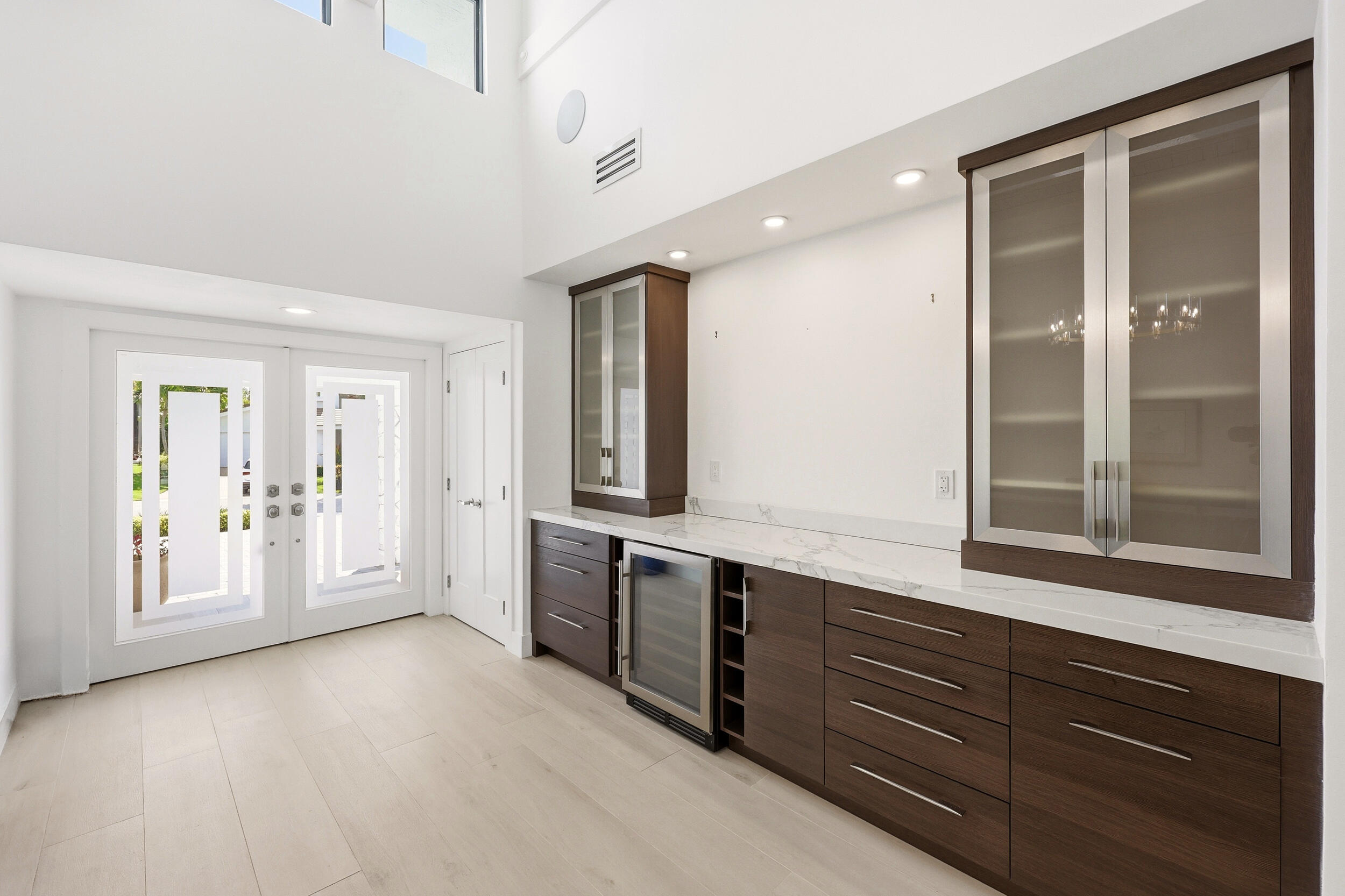 Step inside to a stunning foyer where soaring ceilings, abundant natural light, and wide plank white oak porcelain tile flooring create an unforgettab