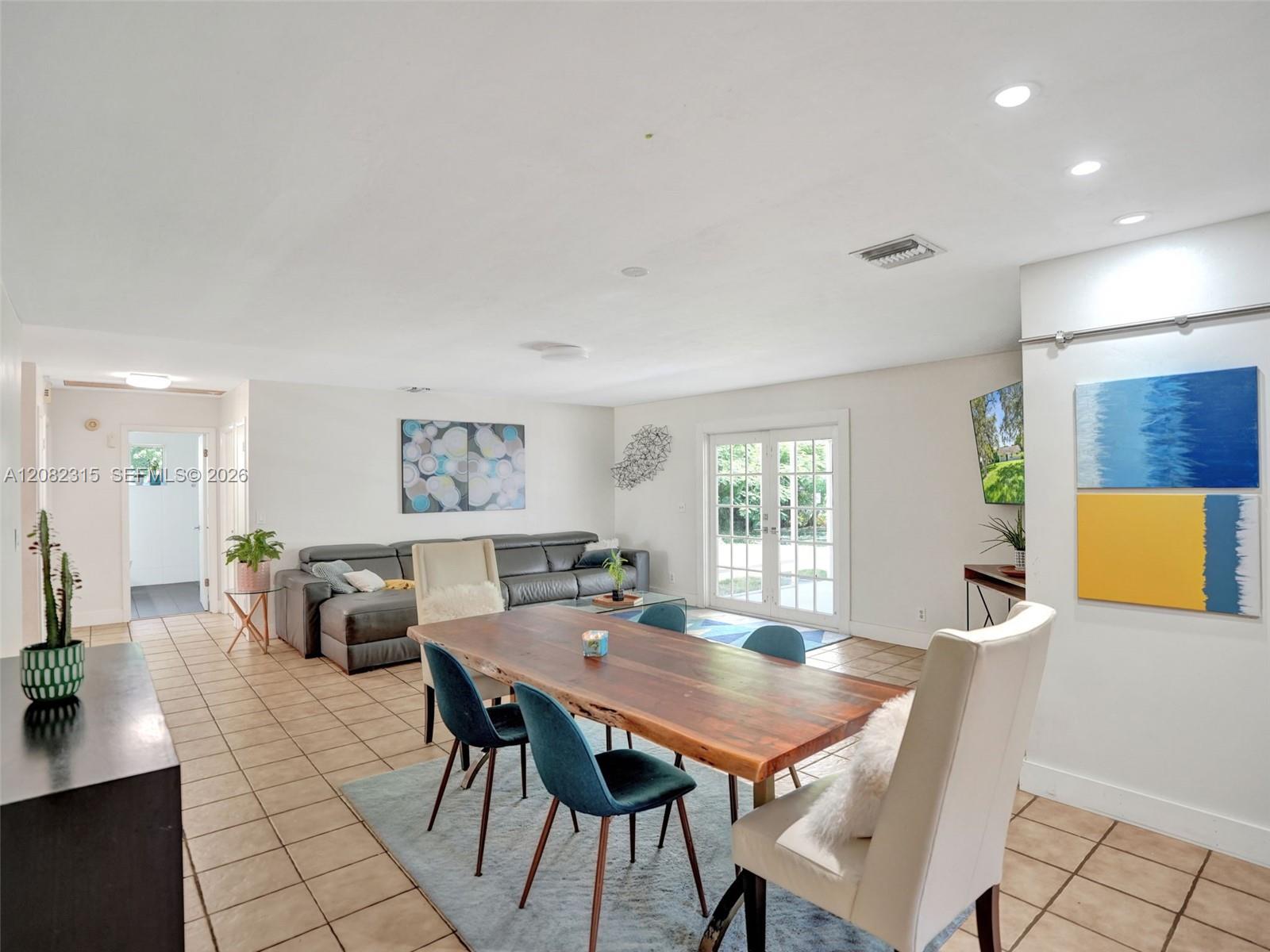 Spacious interior featuring neutral wall tones, large-format tile flooring, recessed lighting, and double glass-paned doors