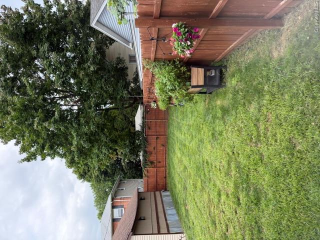 Expansive backyard featuring a privacy fence, mature trees, and a spacious lawn