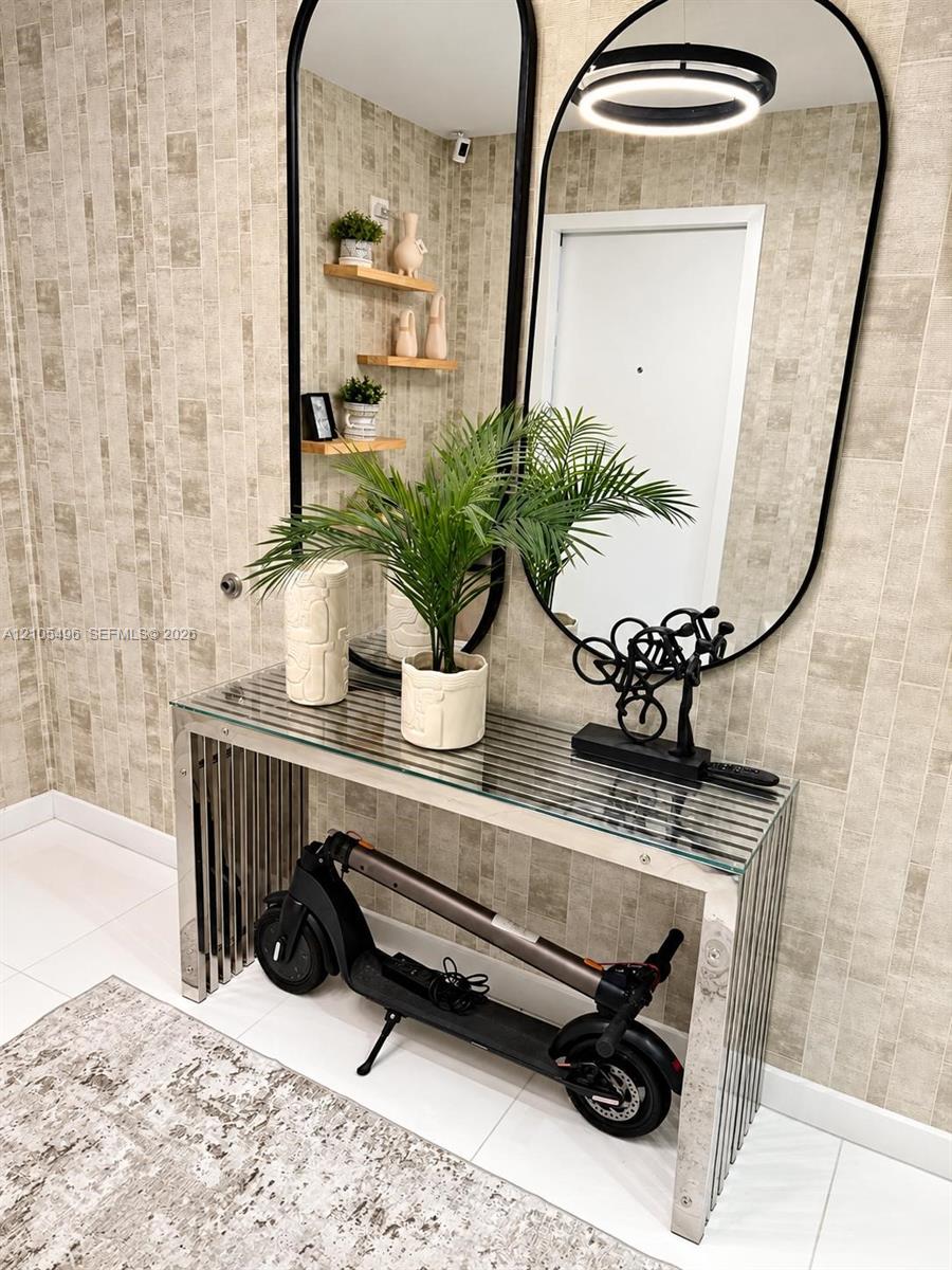 Textured neutral-toned wallpaper, dual floor-to-ceiling arched mirrors with black metal framing, built-in wooden wall shelving, and polished tile floo