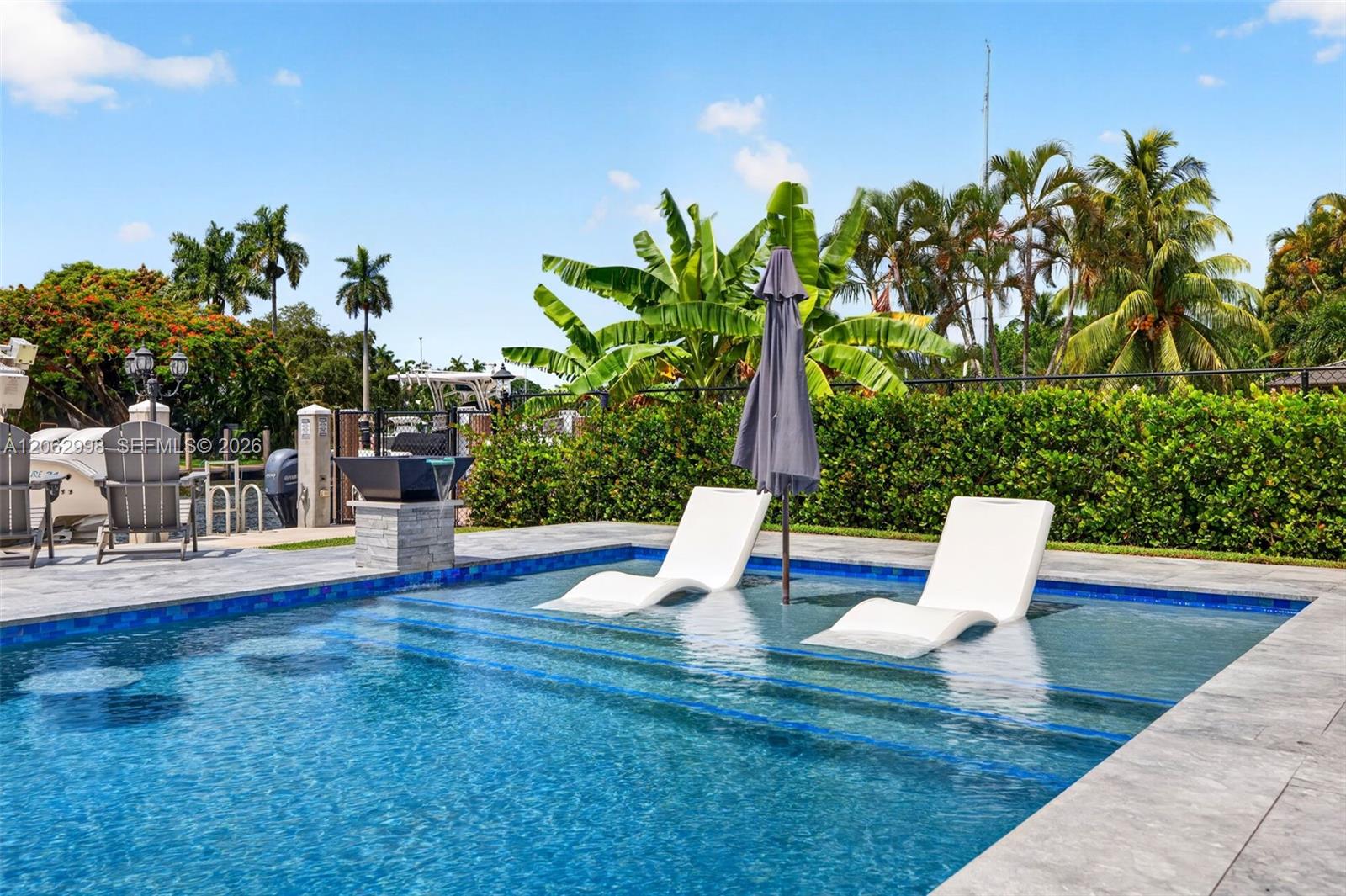 Salt chlorinated pool w/ water features, LED color changing light, sun shelf with umbrella hole and in water stools. Stone decking surrounds the pool