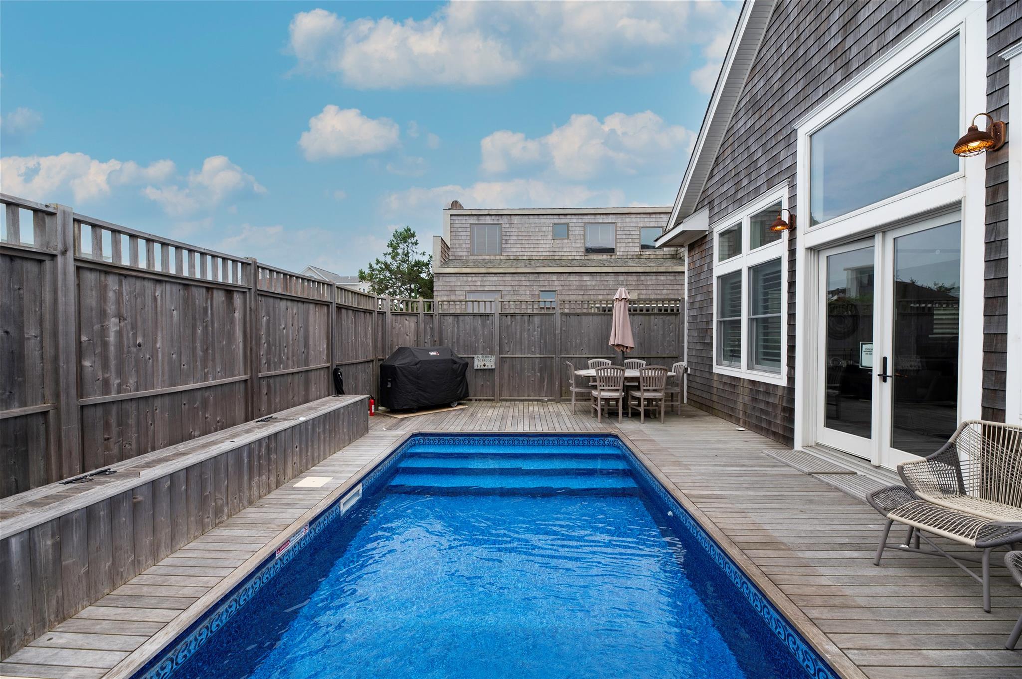 View of pool featuring a wooden deck and a grill