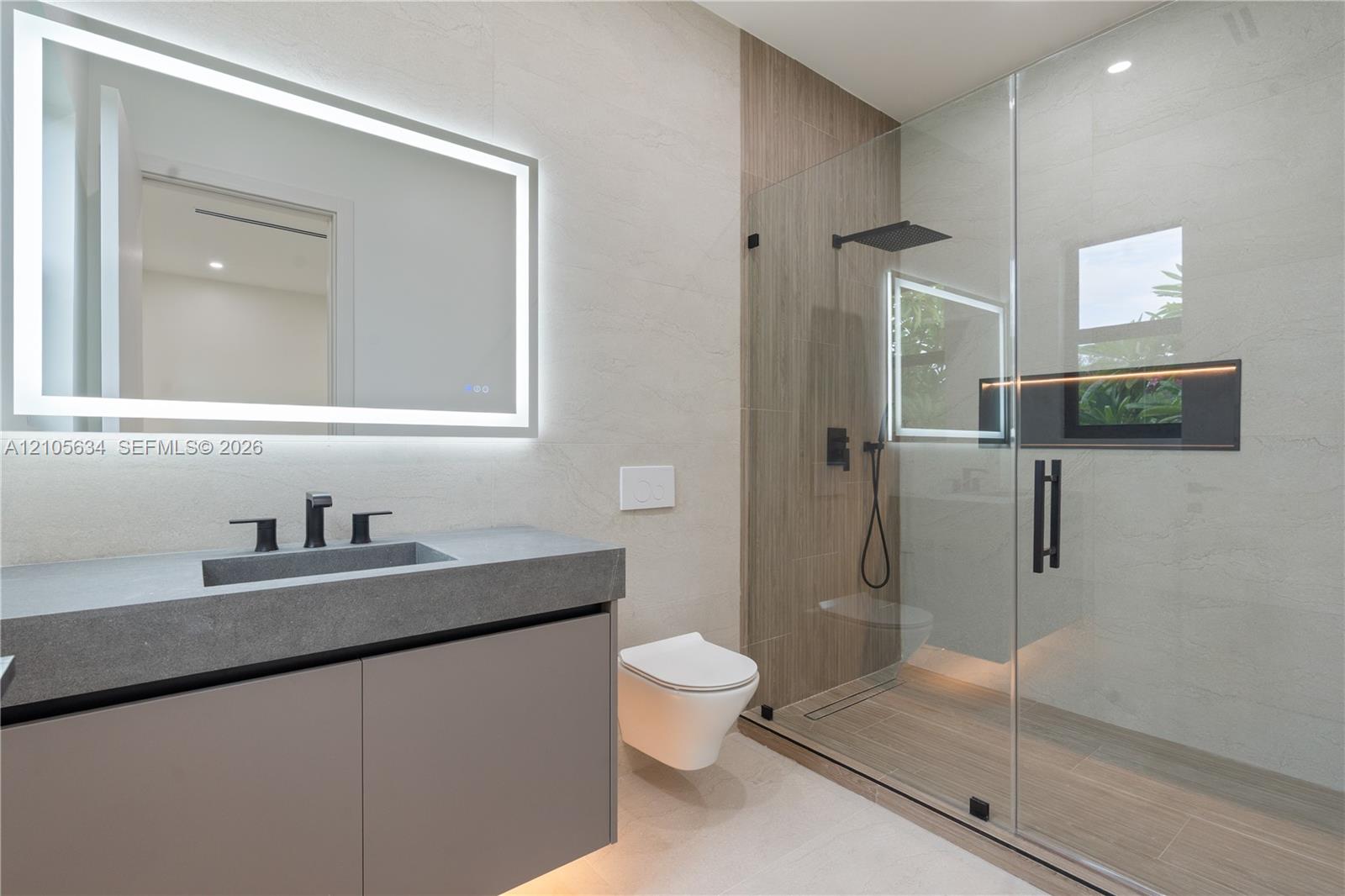 Floating vanity with integrated sink and matte black faucet, wall-mounted toilet, walk-in shower with glass enclosure, wood-finish tile shower wall, a