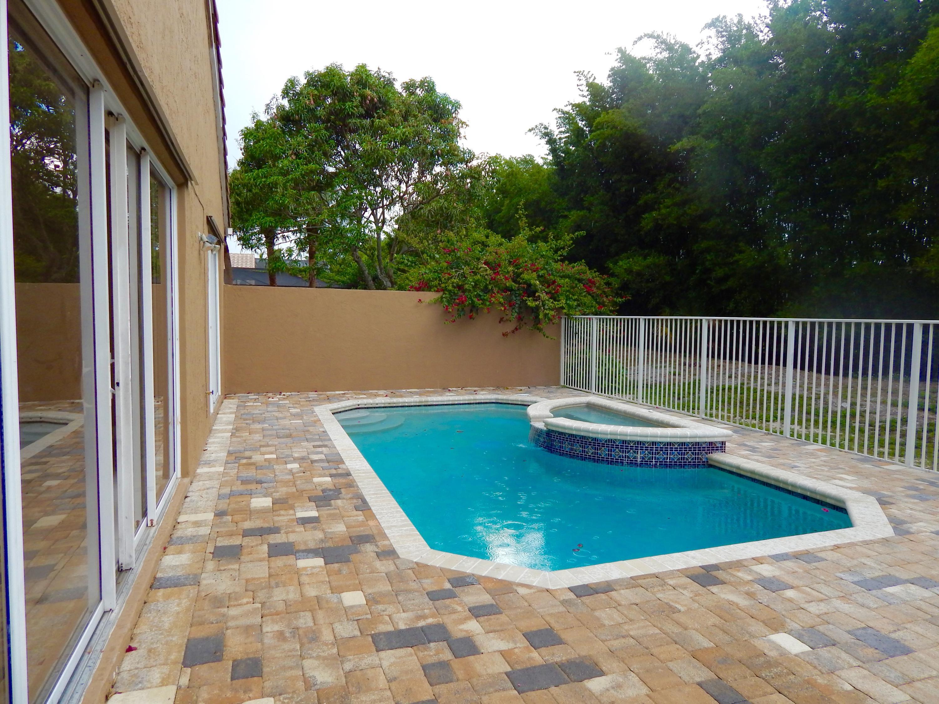 Rectangular swimming pool with an integrated spa, surrounded by multi-tone paver decking