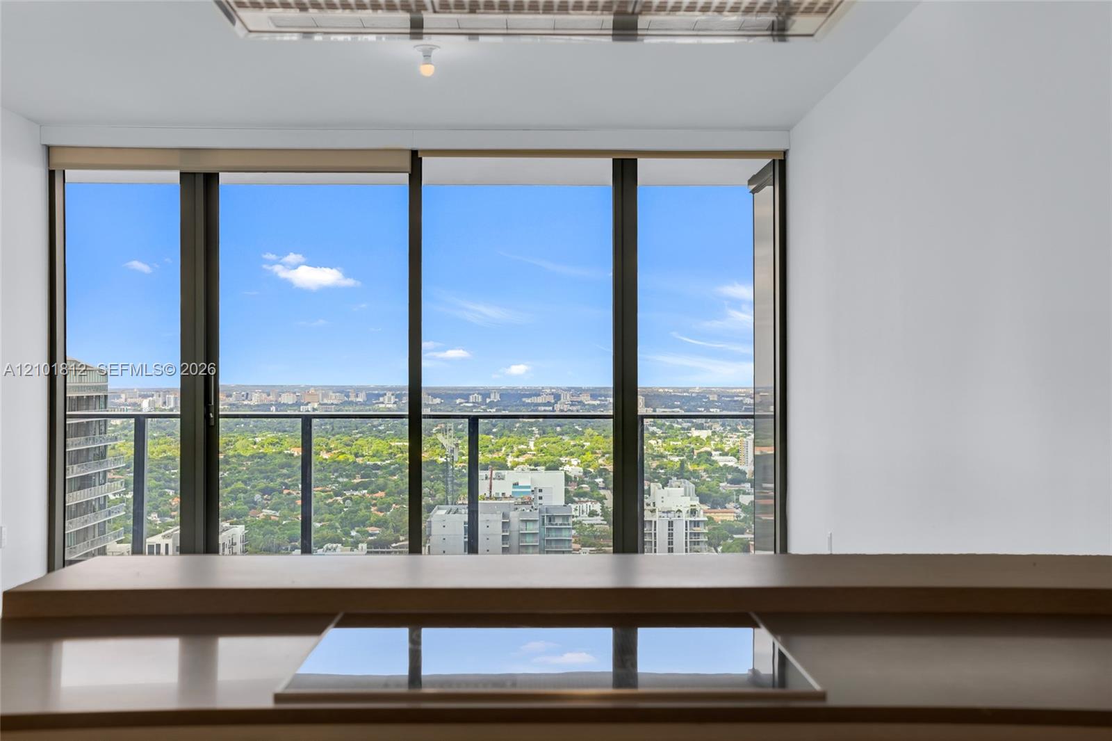 Floor-to-ceiling windows, integrated cooktop, stone-surface countertop, and exterior balcony railing