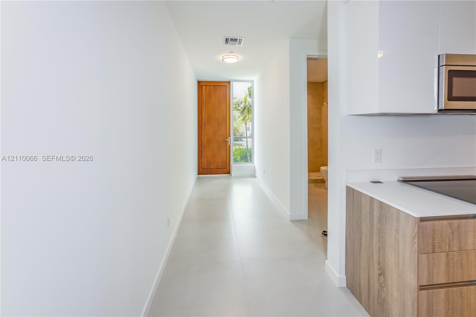 Entryway featuring a solid wood door, large-format tile flooring, and clean-lined cabinetry with a matte finish