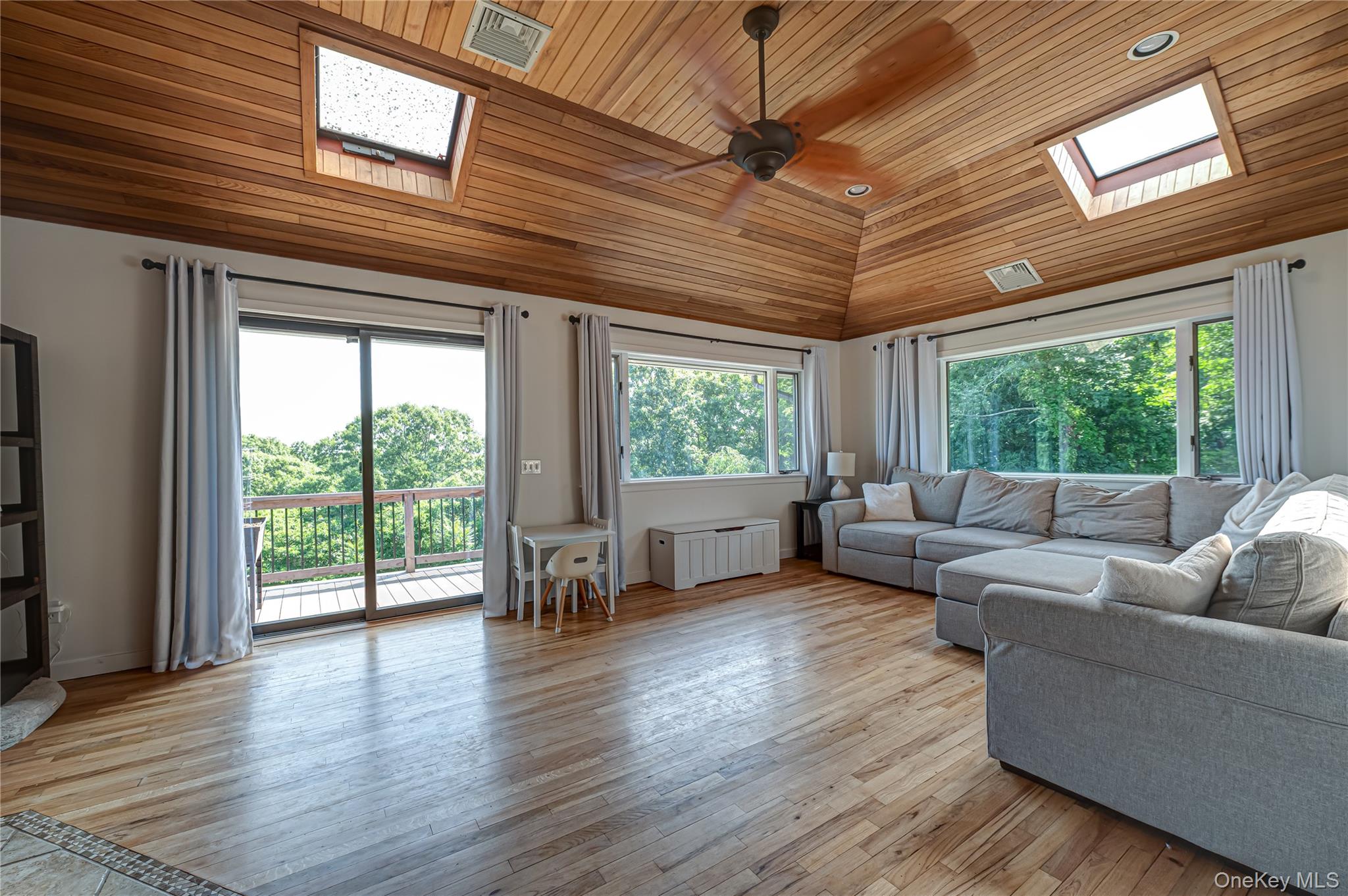 Huge Den with sliders to 2nd side deck overlooking natural 1/2 acre. skylights & natural wood flooring
